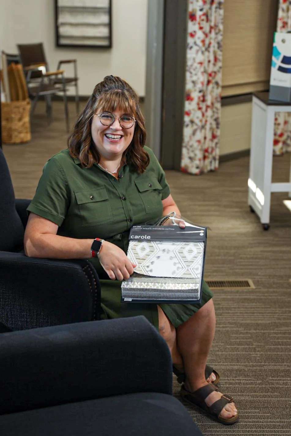 Korin with a drapery fabric book in the Iowa Falls showroom.