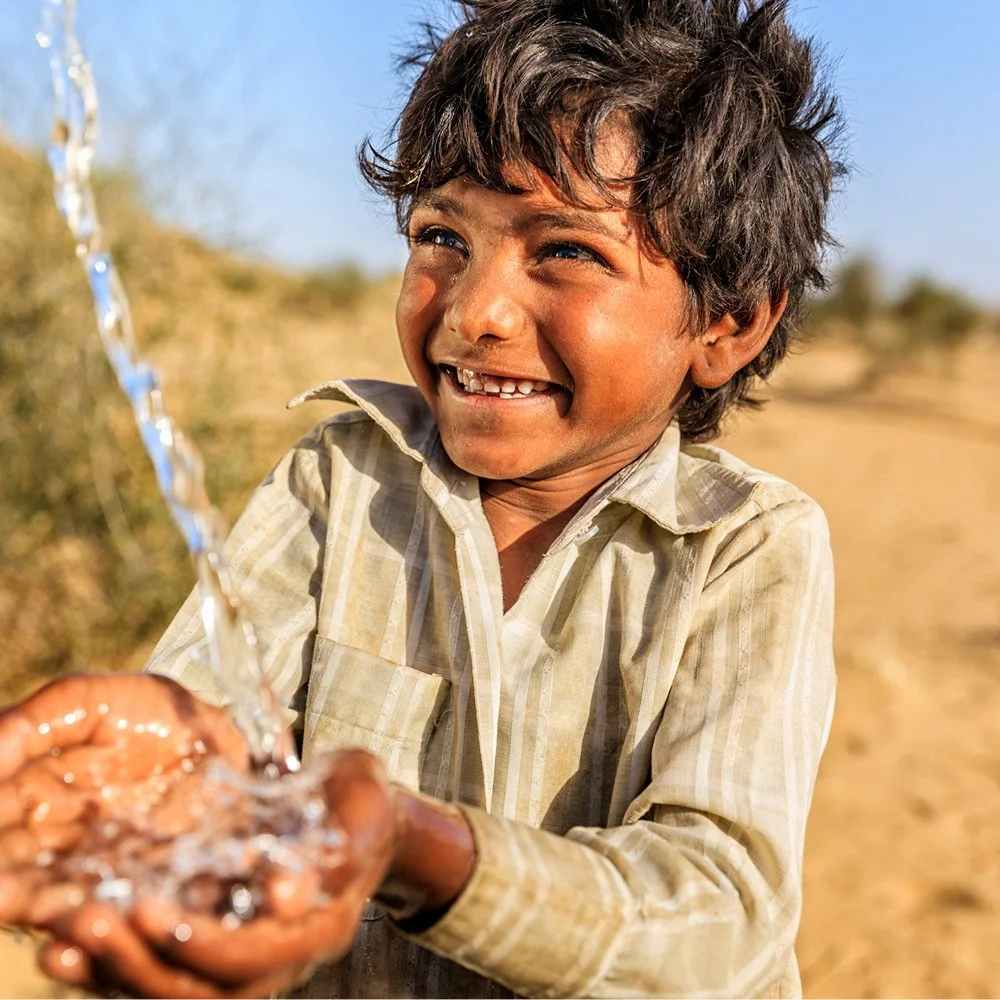 Boy catching fresh water in his hands in underdeveloped country, provided by a non-profit.