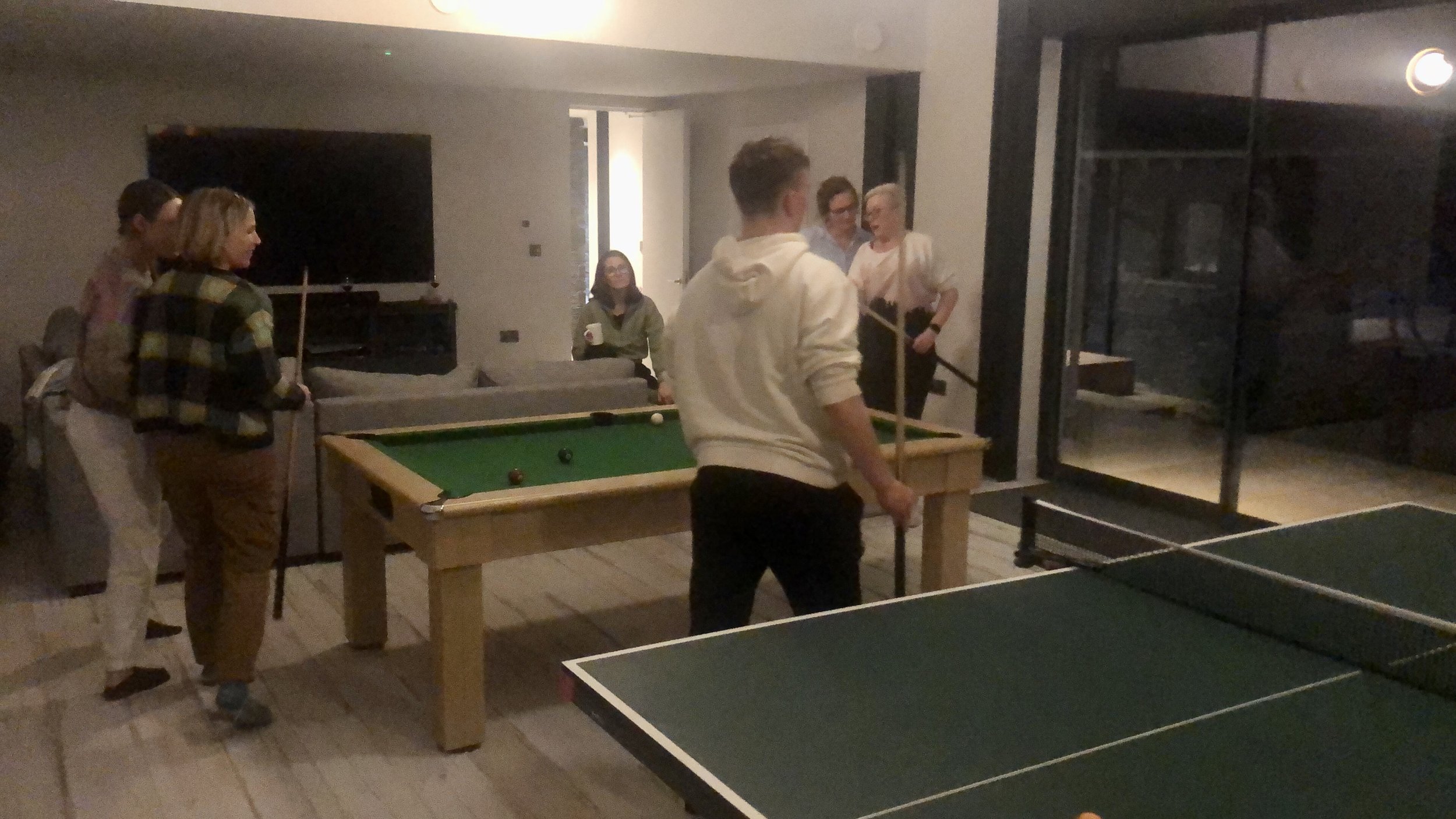 Group of people playing pool and table tennis indoors