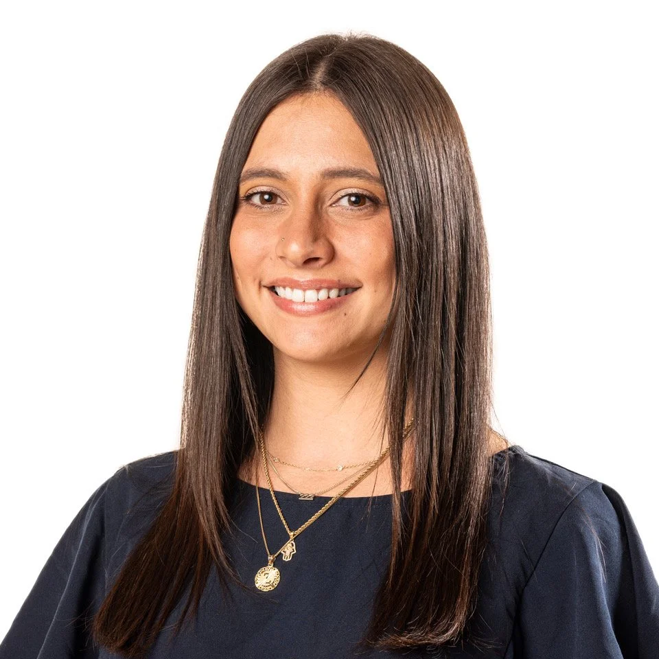 Miami therapist with straight brown hair smiling, wearing a dark top and layered gold necklaces, against a white background.