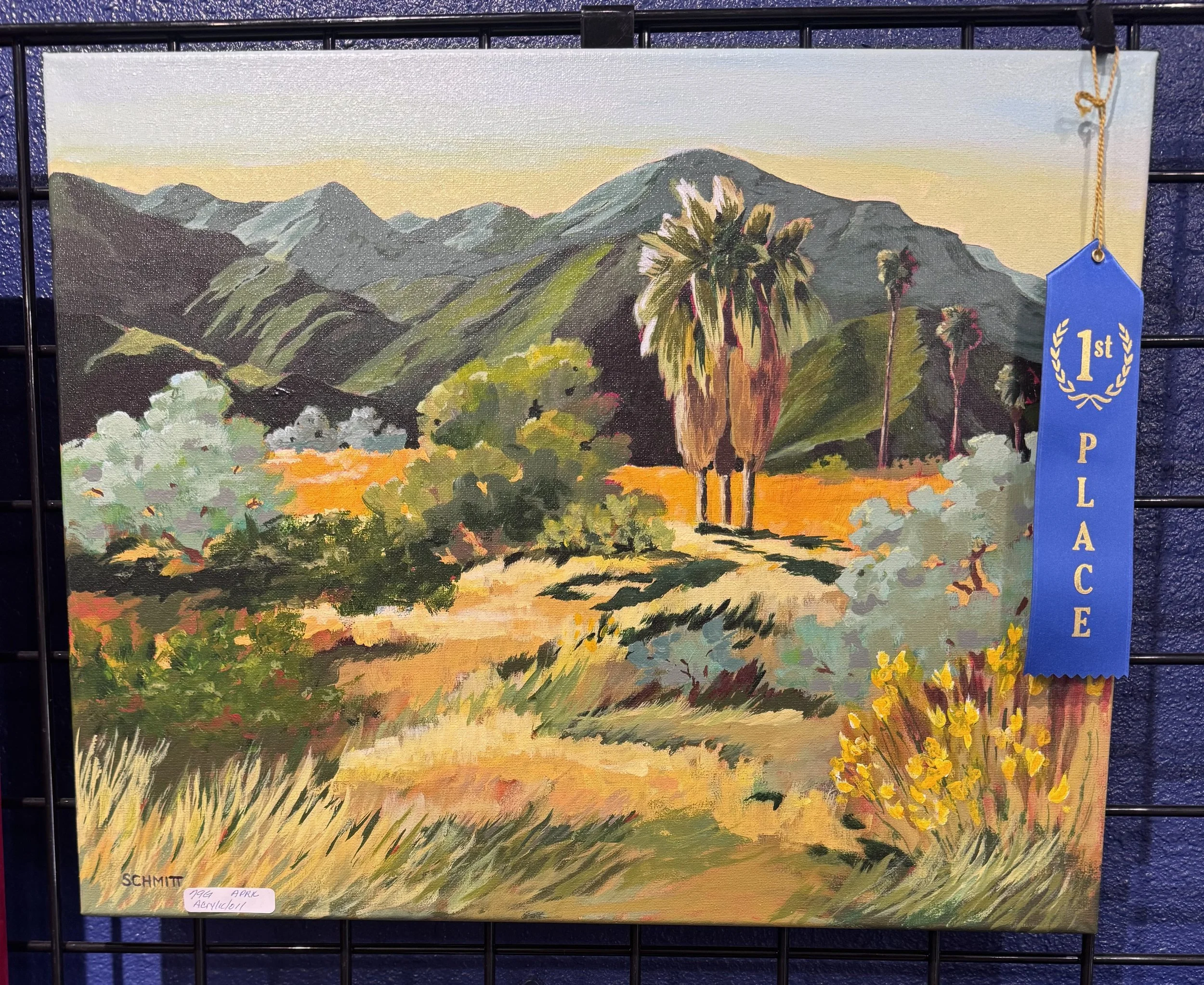 A landscape painting of mountains, trees, and a sunset sky, with a blue ribbon indicating first place awarded.