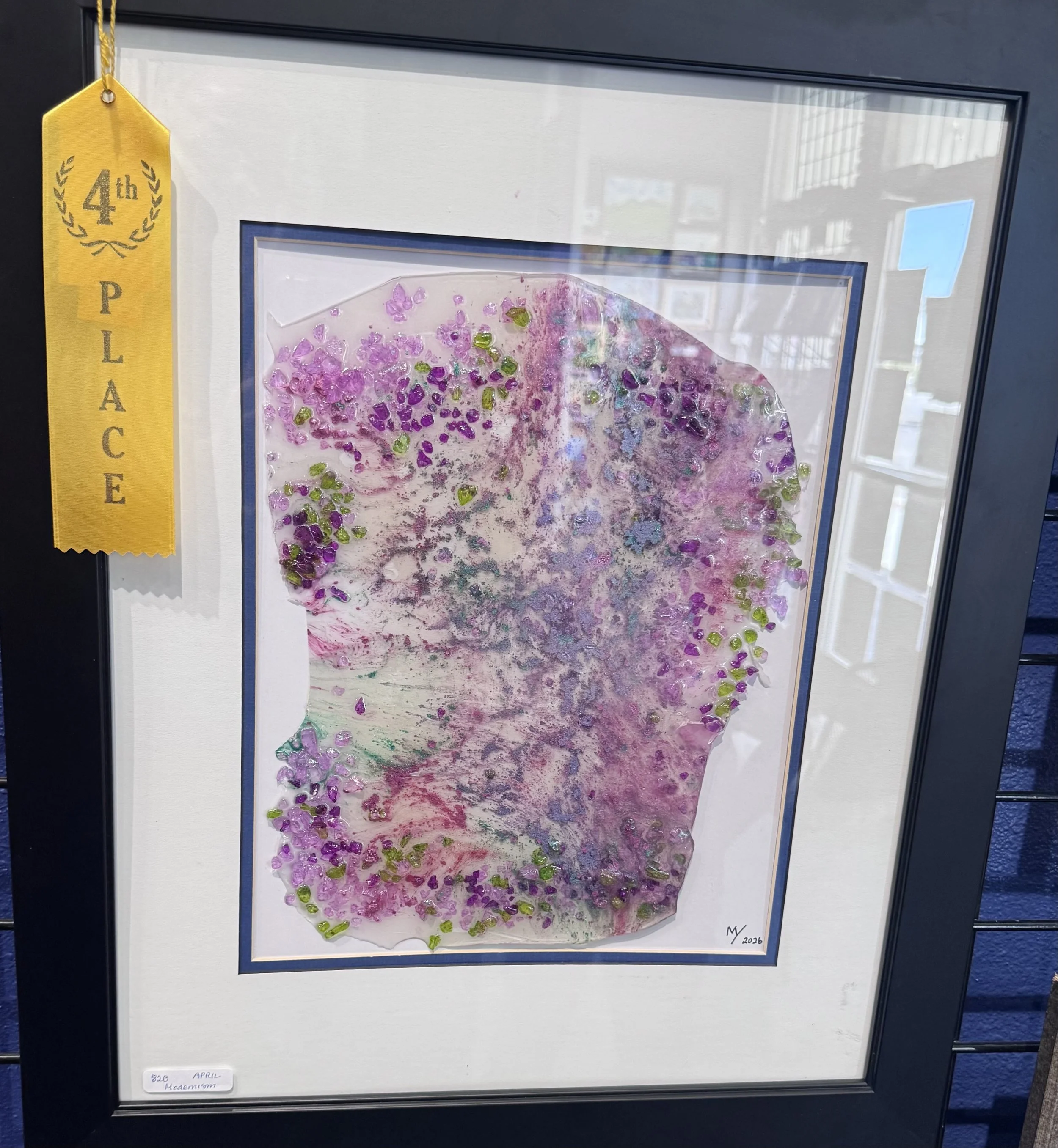 Framed abstract artwork with pink and green textured splashes, featuring a yellow ribbon indicating 4th place in an art competition, signed 'MV 2026'.