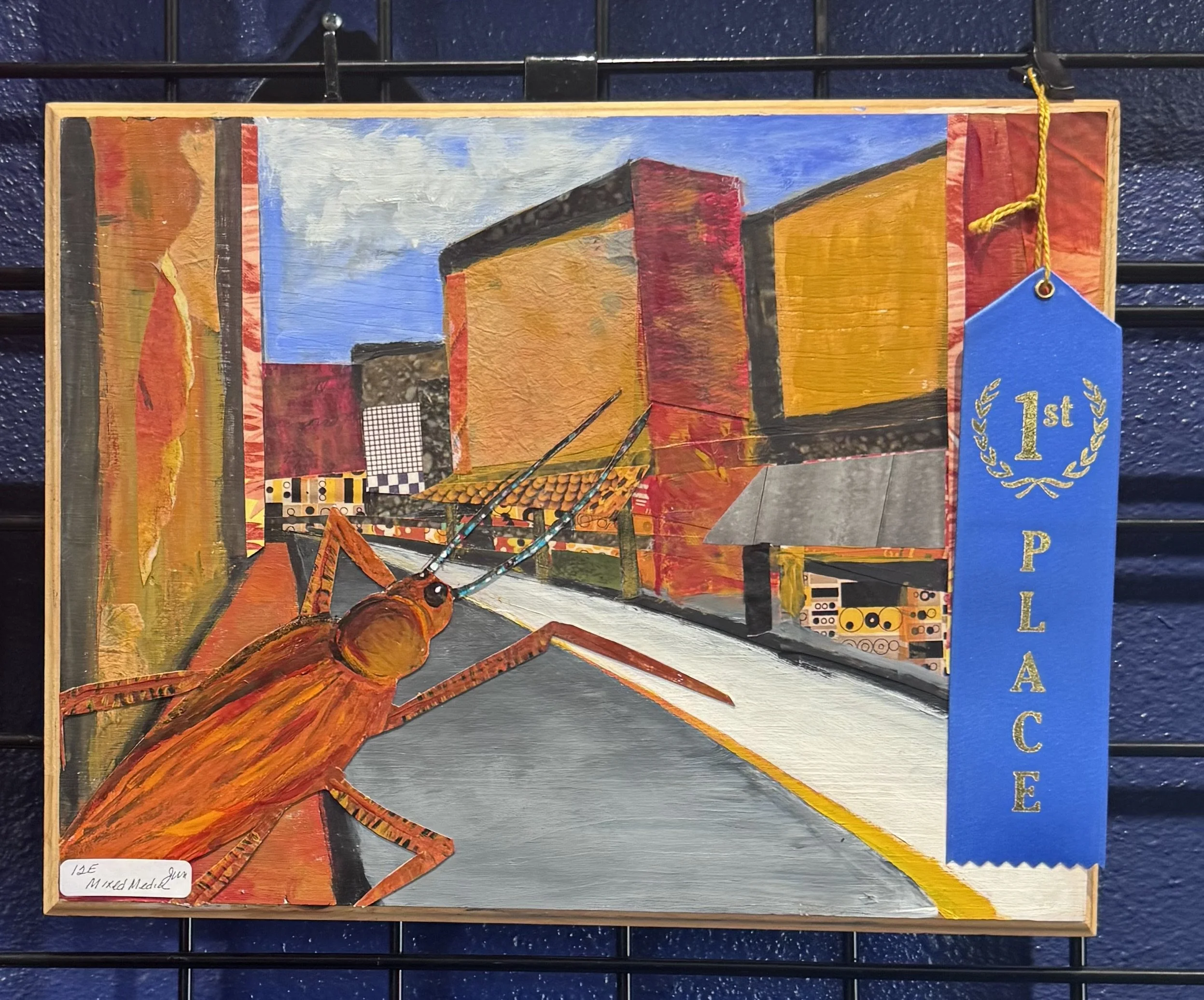 A colorful abstract painting with geometric shapes and textured layers, featuring a blue sky in the background and a prominent orange and red insect in the foreground. There is a blue ribbon with gold lettering indicating a first place award attached