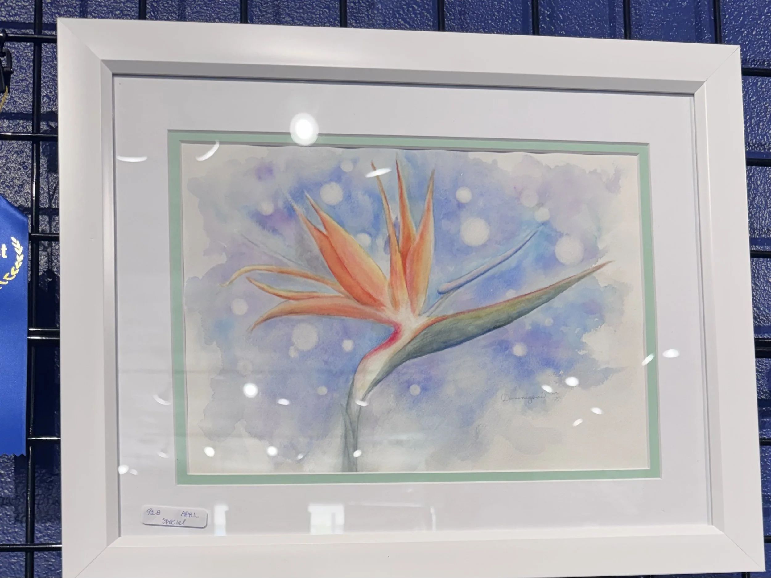 Watercolor painting of a tropical flower with orange petals and green stem against a blue and purple background with white bubbles.