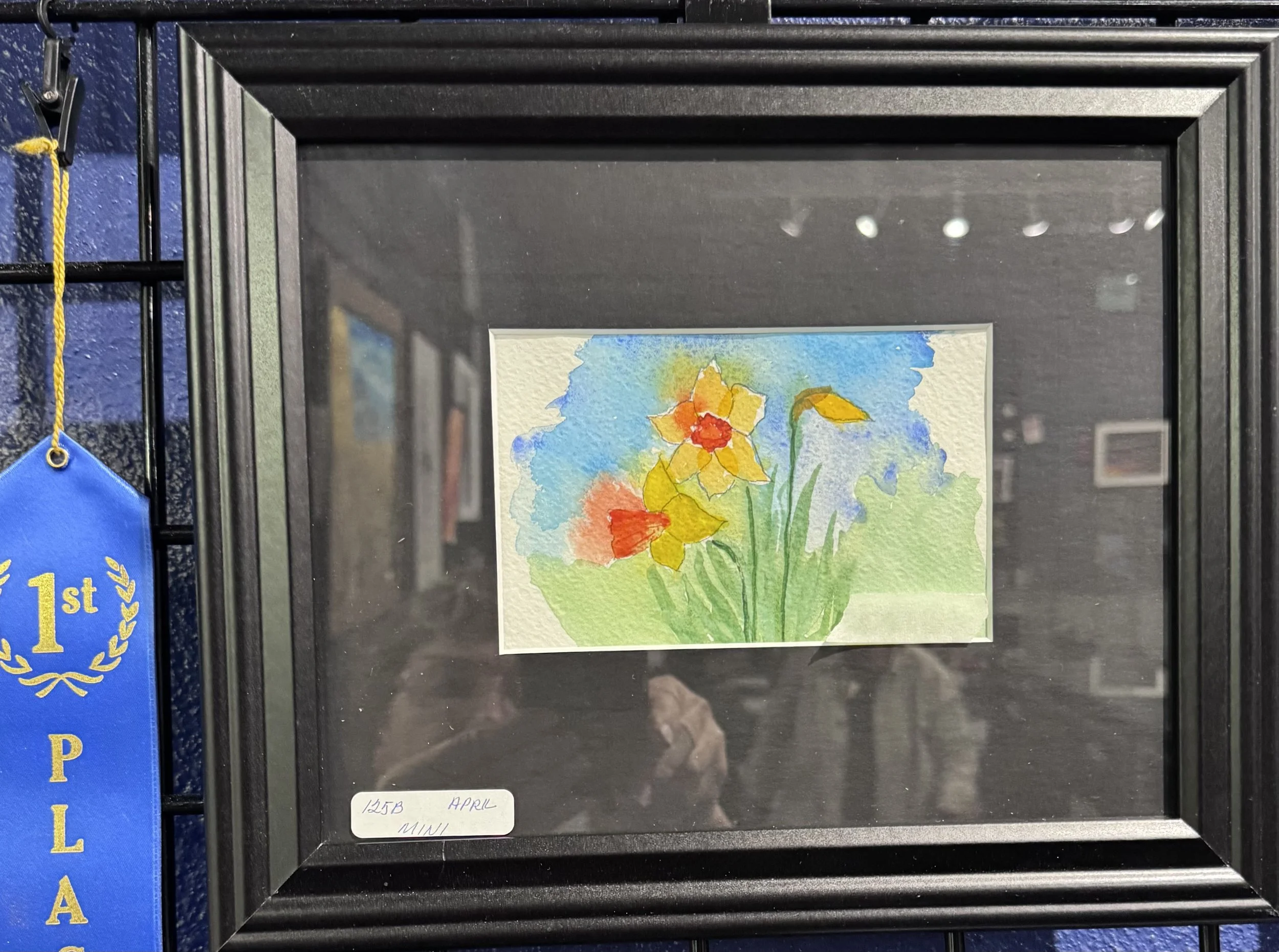 Framed watercolor painting of flowers, with a black frame and glass cover.