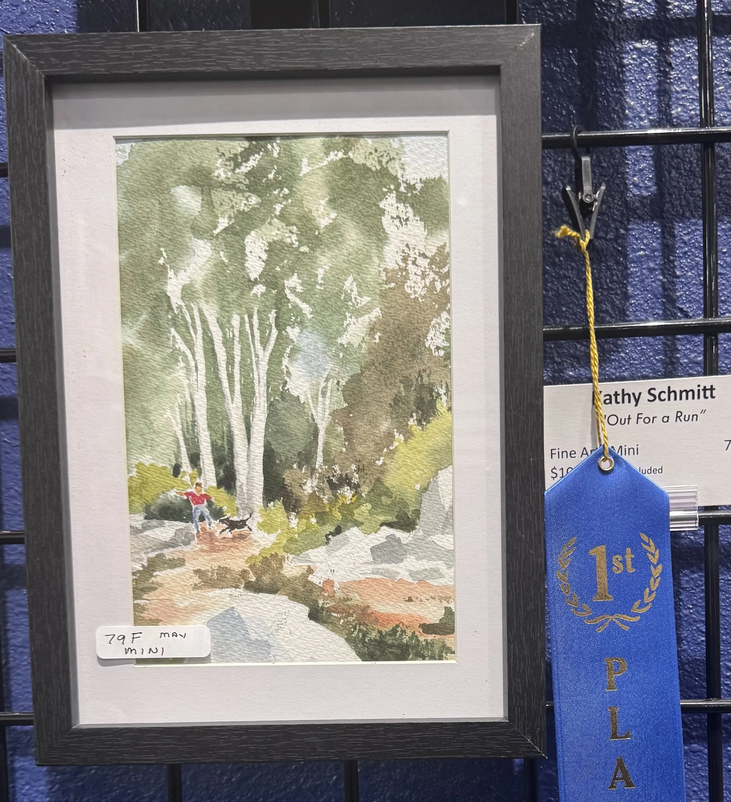 Watercolor painting of a large tree with green leaves and a person in a red shirt and blue pants standing underneath, with grass and other trees in the background.