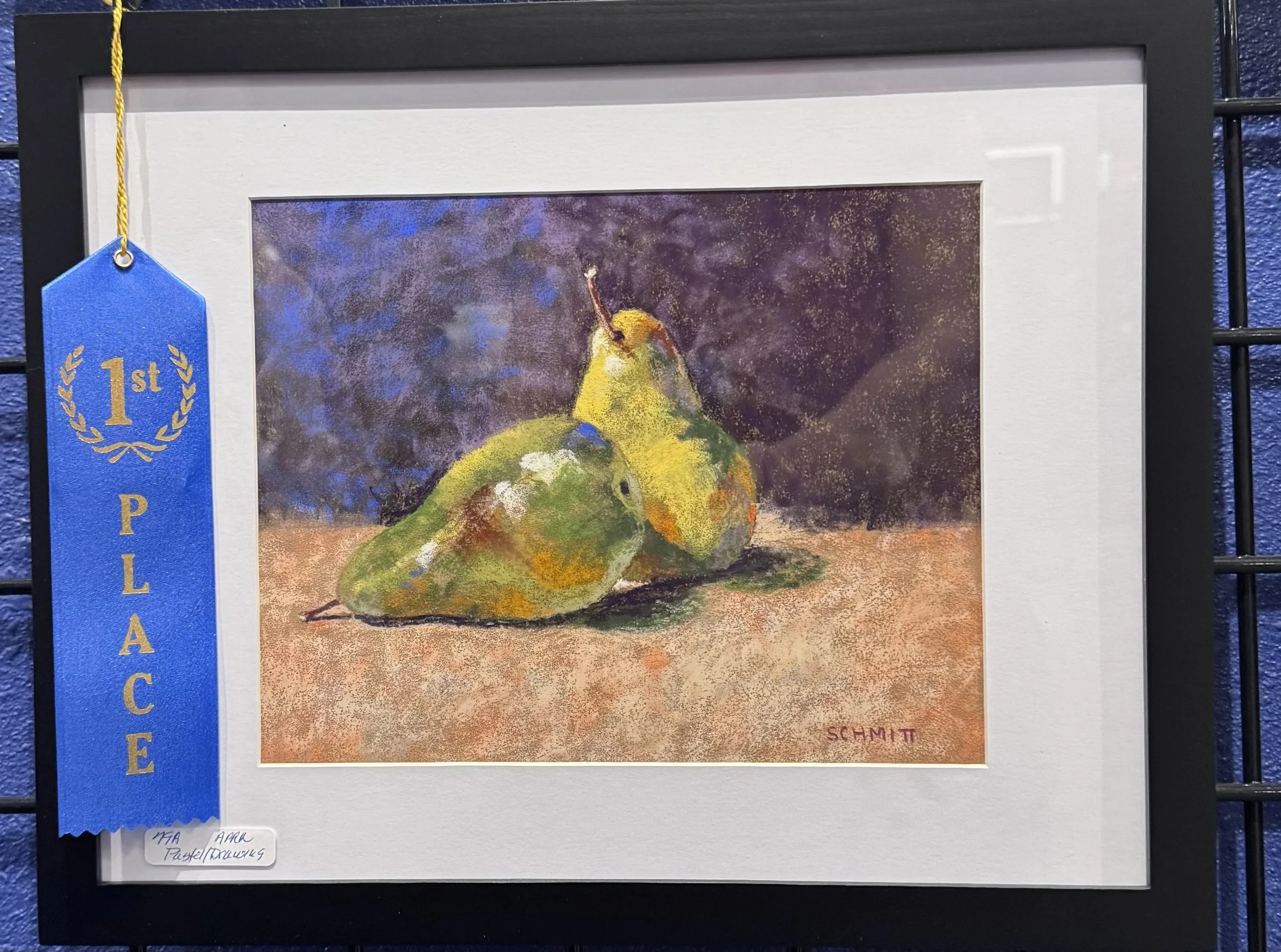 Colorful painting of two pears, signed by Schmitt, displayed with a blue ribbon that reads '1st Place' on a black display stand.
