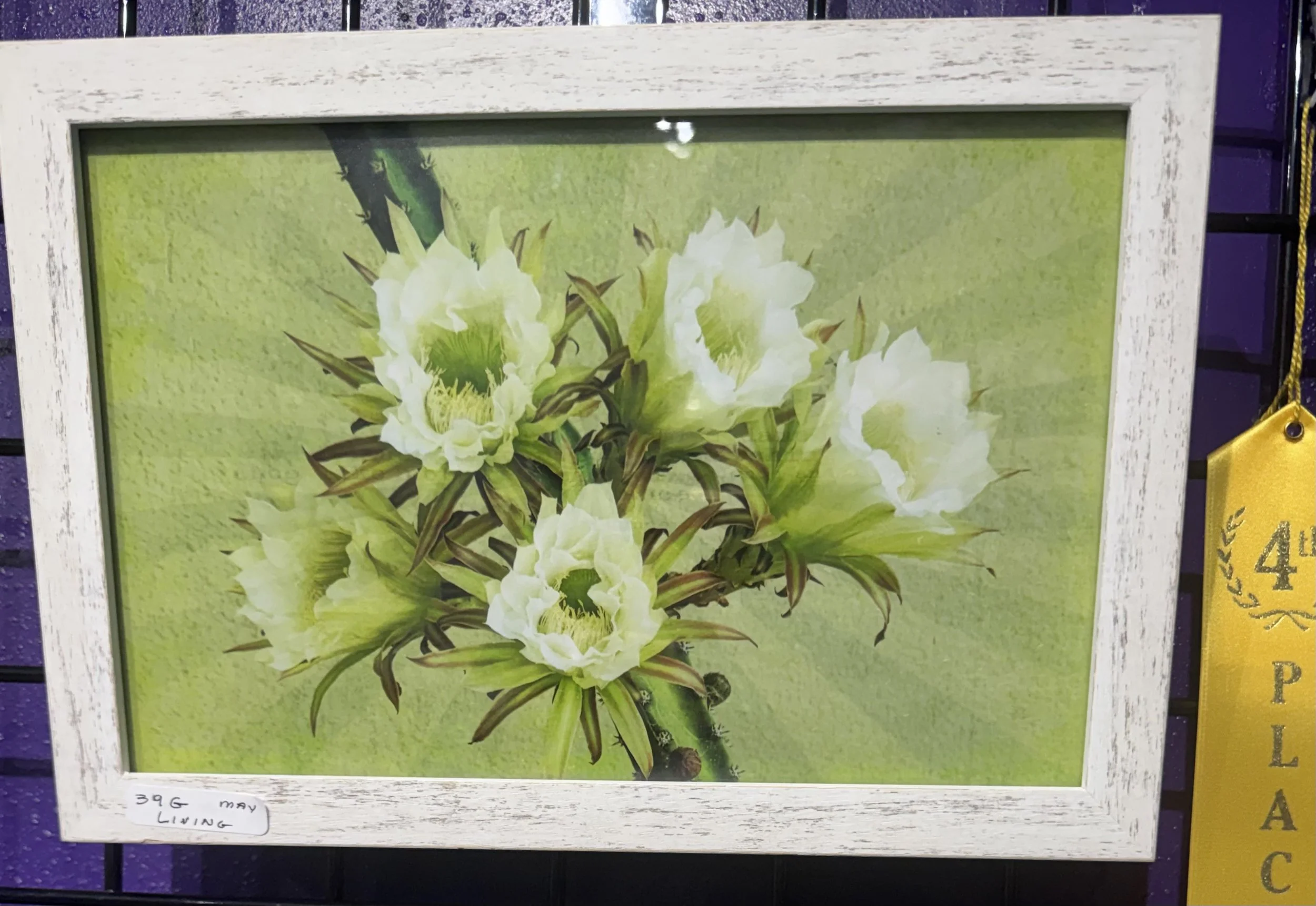 A framed picture of white flowers with green stems and leaves, displayed against a yellow-green background.