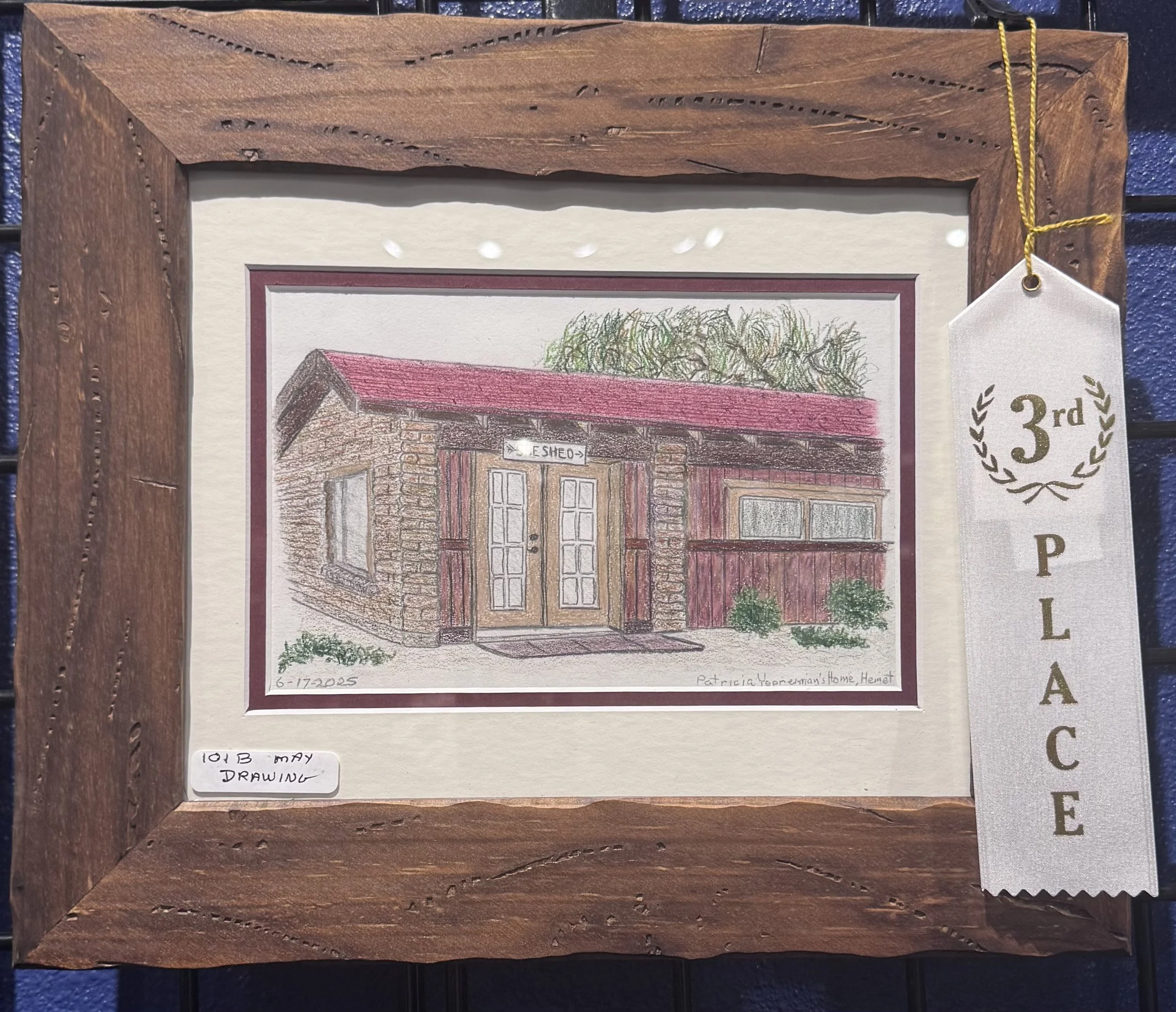 This is a framed drawing of a rustic building with a red roof, gray stone walls, and multiple windows, accompanied by a small green shrub at the bottom right corner. The drawing is labeled with the date '6-17-2025' and the artist's name 'Patricia Ter
