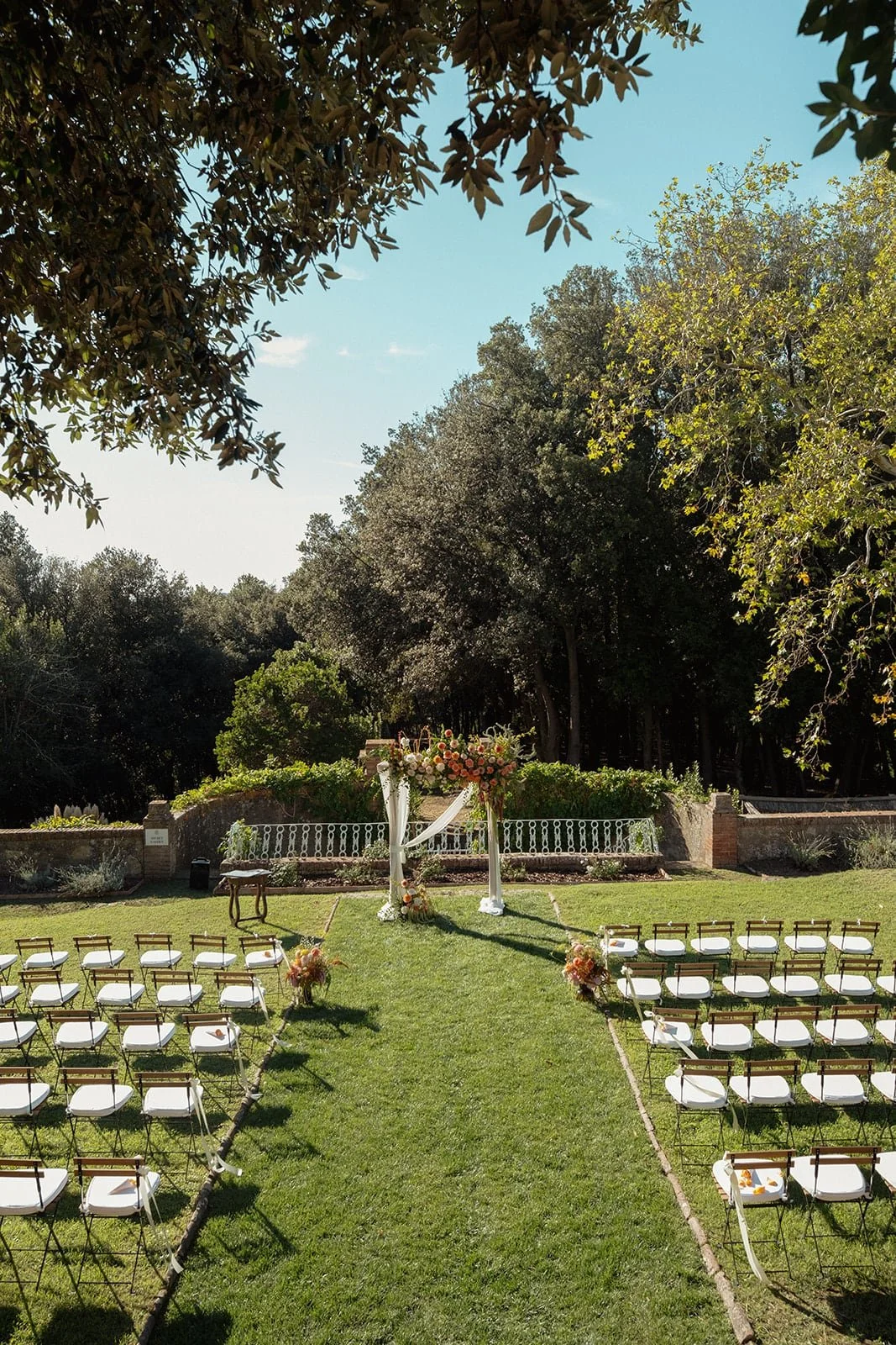 The outdoor ceremony space at Villa Lena, arranged with wooden chairs and floral details, set in the Tuscan landscape before the guests arrive.
