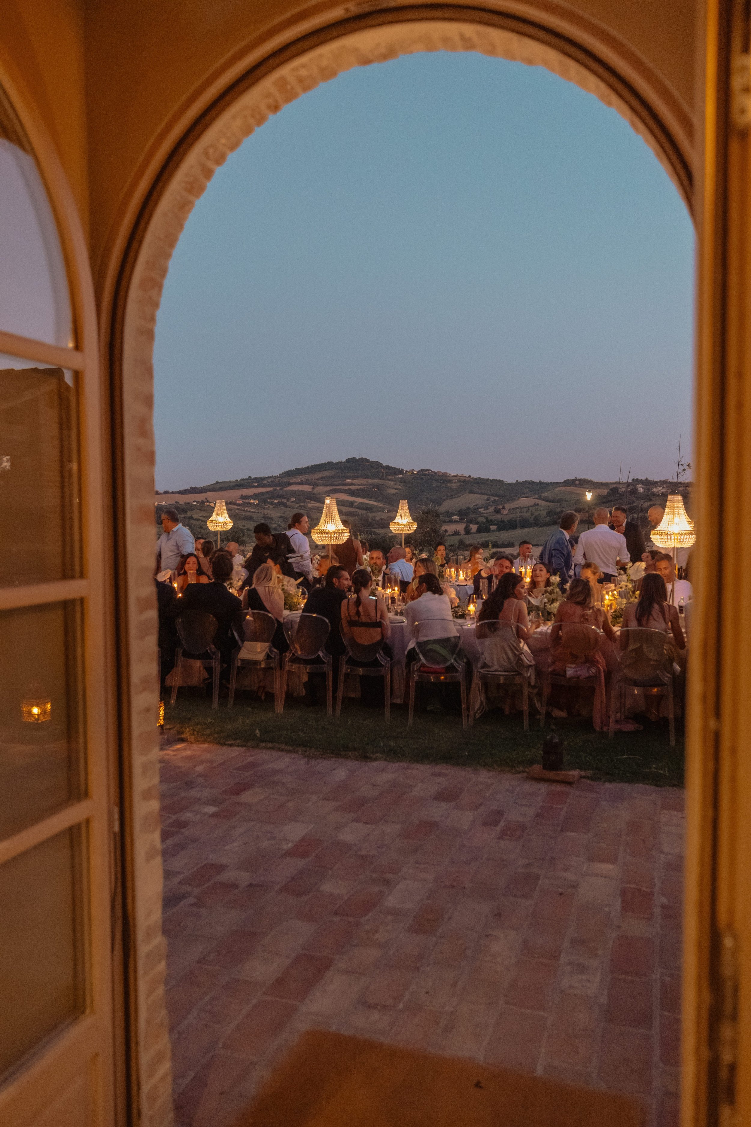 An elegant outdoor wedding dinner at a Tuscan villa, set against rolling hills and warm evening light, creating an intimate and refined celebration.