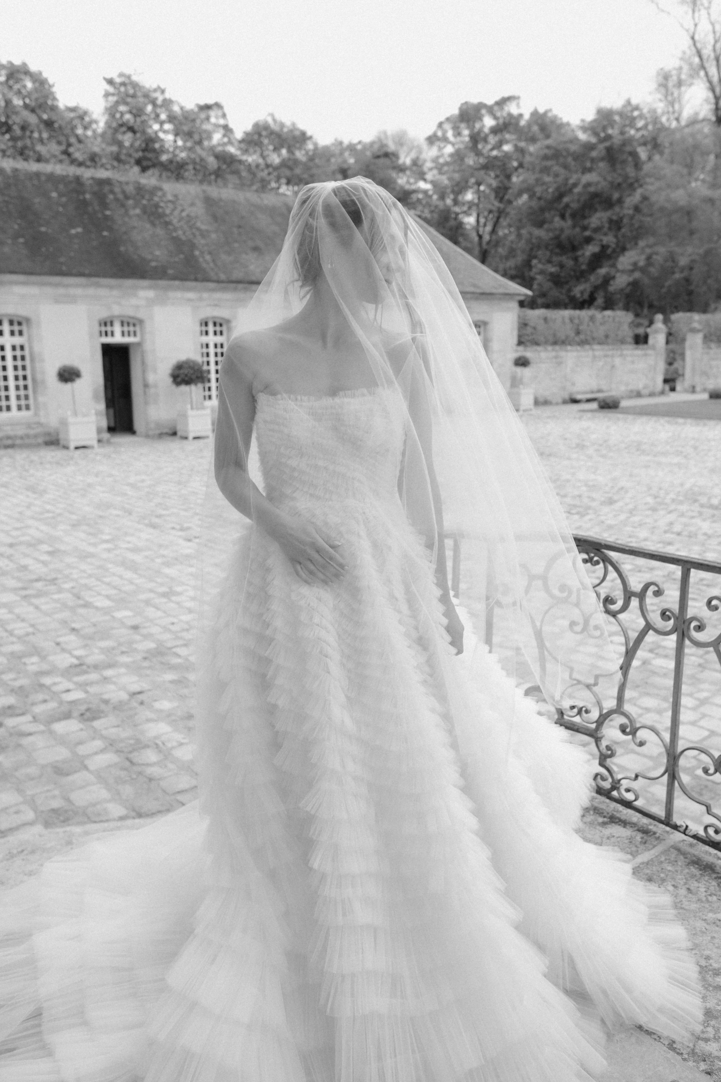 An editorial bridal portrait captured at a French château, featuring a couture ruffled tulle gown and timeless European elegance for a refined destination wedding.