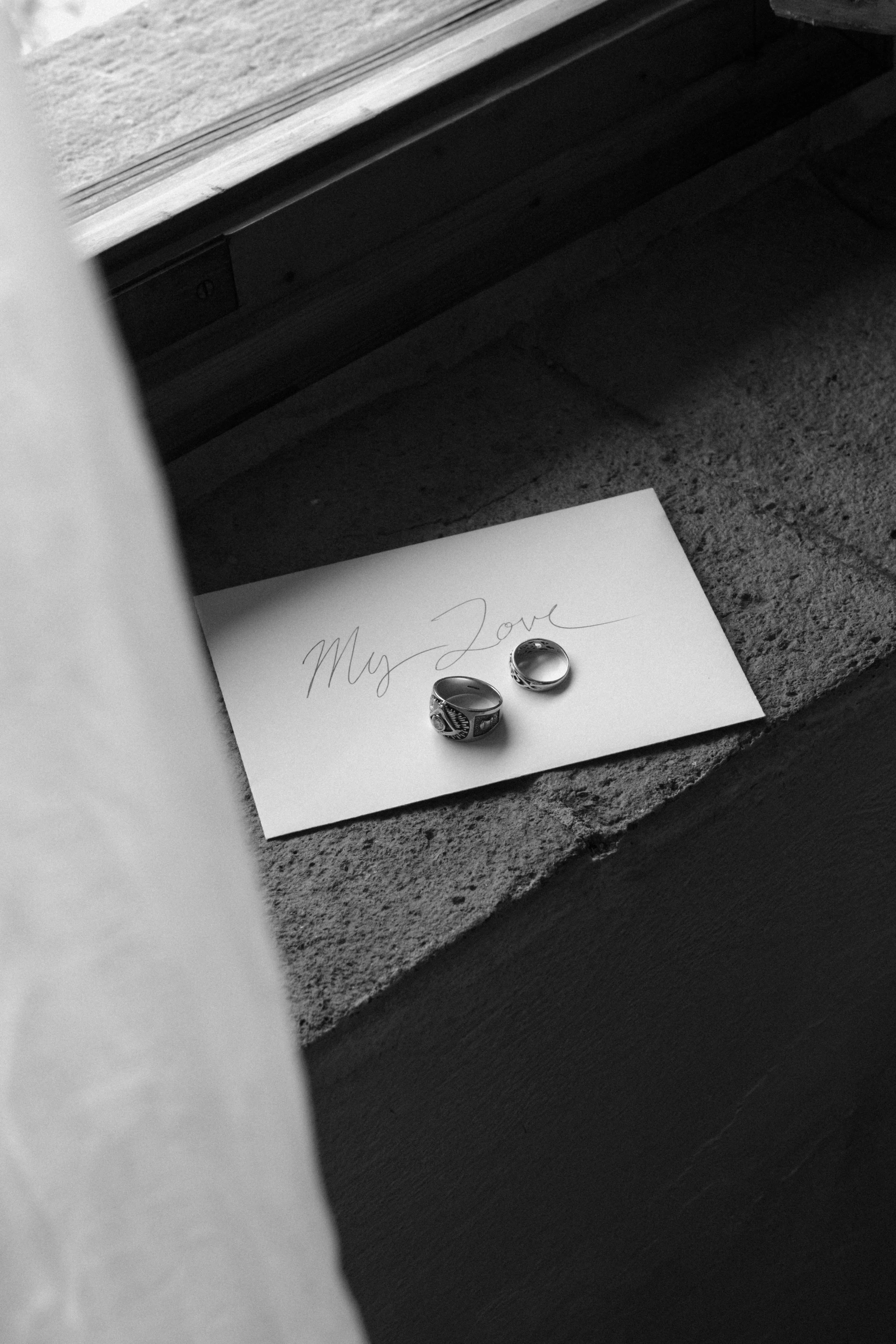 Wedding rings resting on a handwritten love letter, photographed in natural light with an editorial, fine-art approach at Castello di Bibbione Tuscan villa.