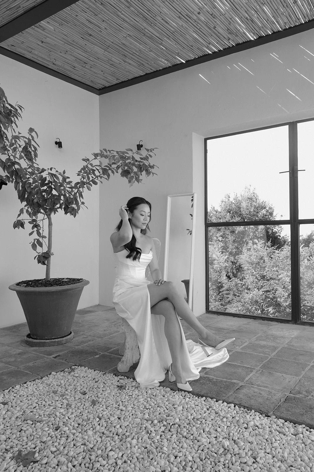 The bride pauses in a serene architectural space, adjusting her hair as sunlight filters through the villa.
