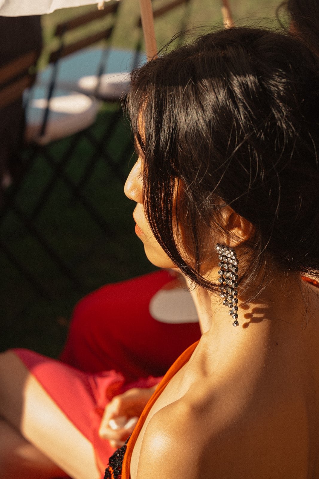 A close portrait of a guest wearing statement earrings, photographed in warm sunlight during the outdoor ceremony.