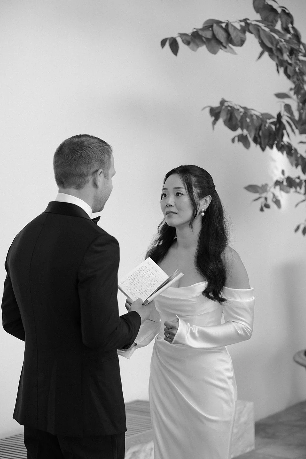 The bride listens attentively during the exchange of vows, captured in a contemporary Tuscan setting with clean architecture and warm tones.