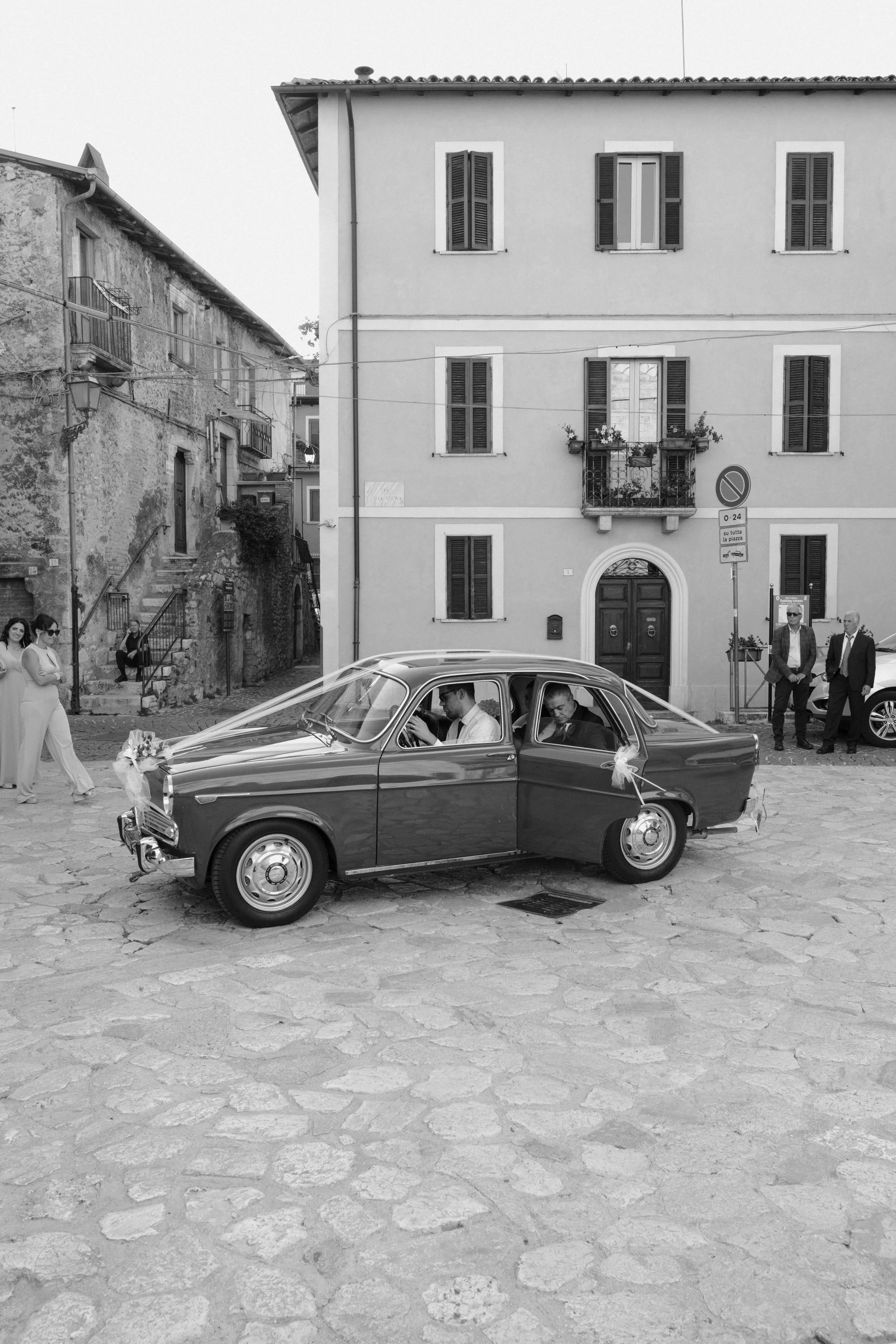 Vintage wedding car arrival in a Tuscan village square, capturing authentic Italian charm and a timeless destination wedding atmosphere.