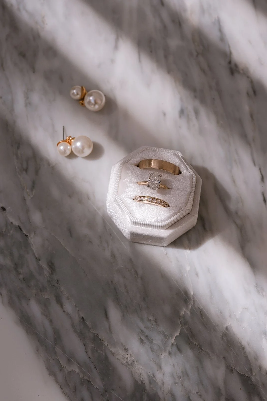Wedding rings and pearl earrings arranged in soft natural light, captured with an editorial eye in Tuscany.