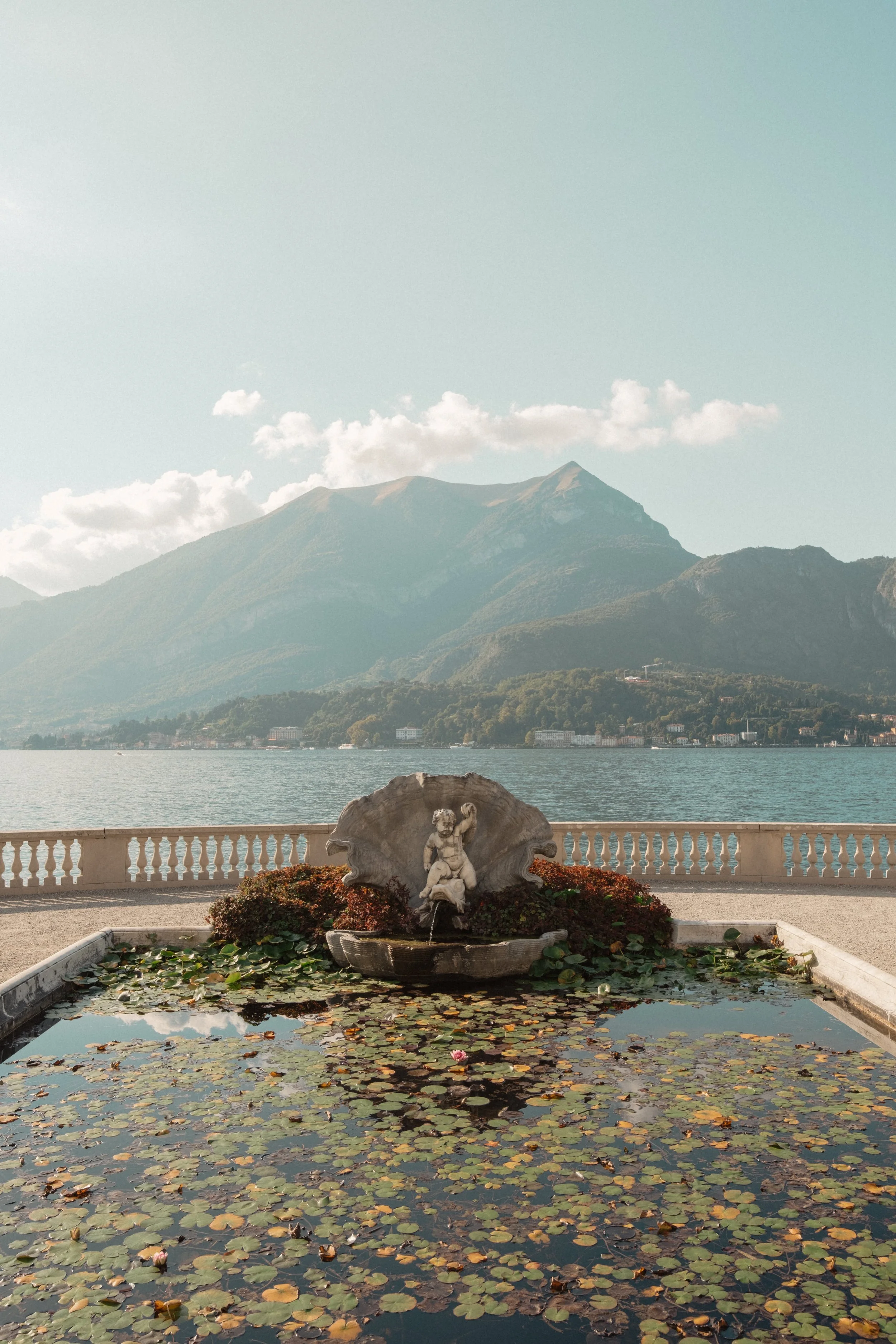 A serene view of Villa Melzi on Lake Como, featuring a historic fountain, lily pond, and dramatic mountain backdrop—perfect inspiration for elegant elopements and intimate weddings.