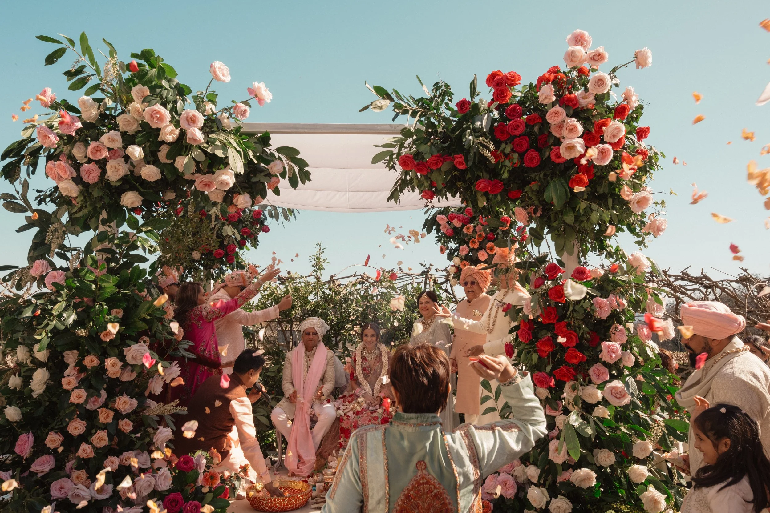 Traditional Indian wedding ceremony in Italy with floral mandap, rose petals, and family celebrating during a luxury destination wedding