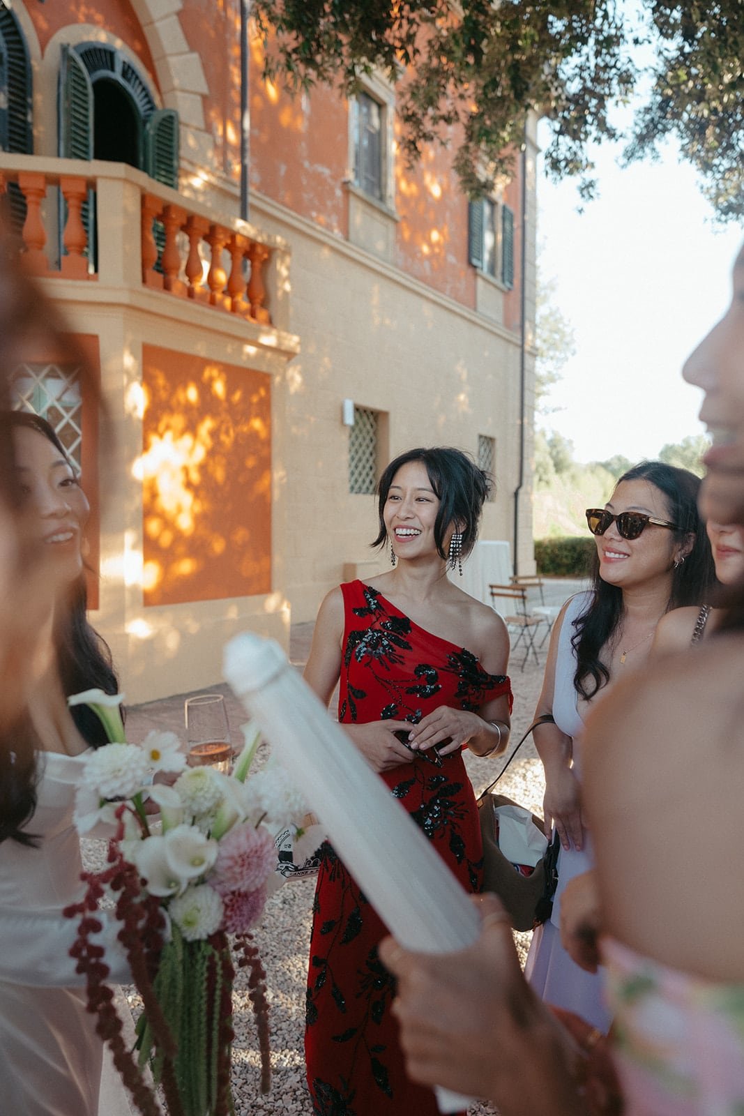 Guests share laughter and conversation during cocktail hour, photographed in golden light beside the Tuscan villa.