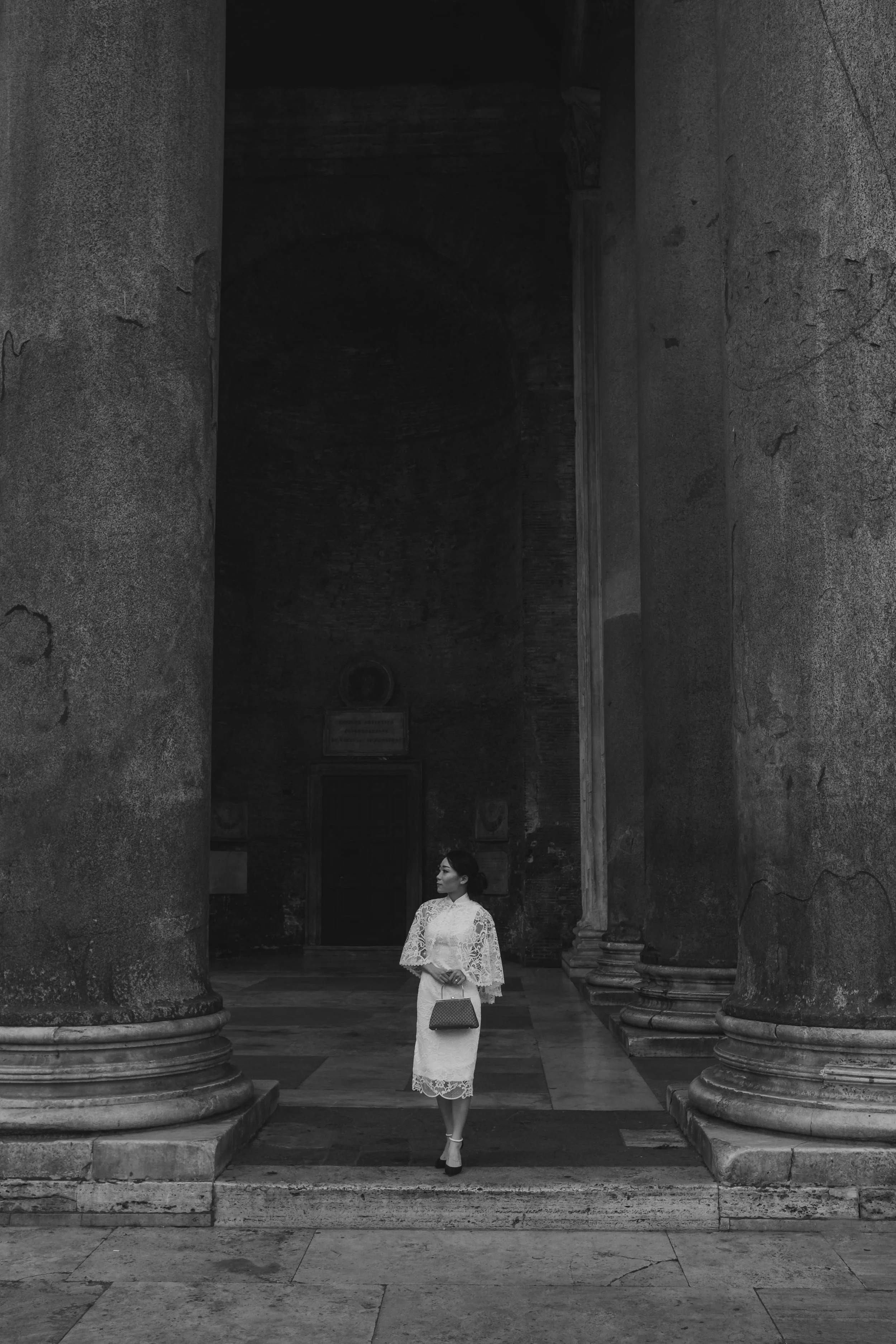 Black and white portrait of a bride standing between the Pantheon columns in Rome