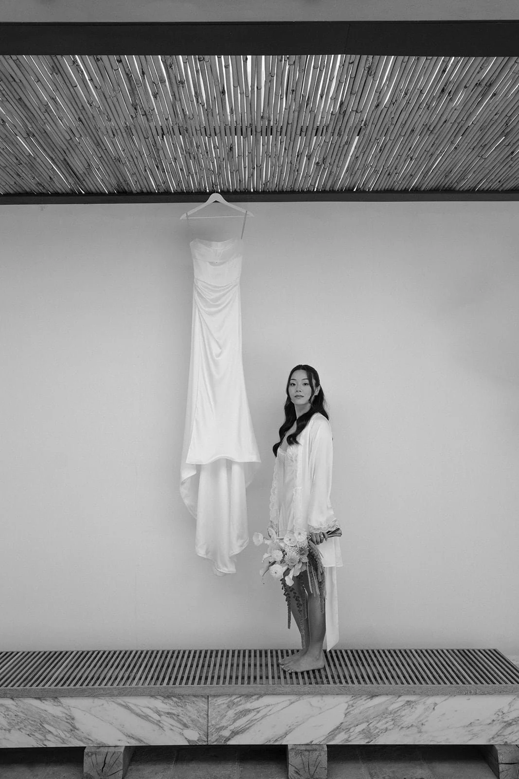 A minimalist black and white portrait of the bride seated alone, framed by architectural lines and natural light in Tuscany.