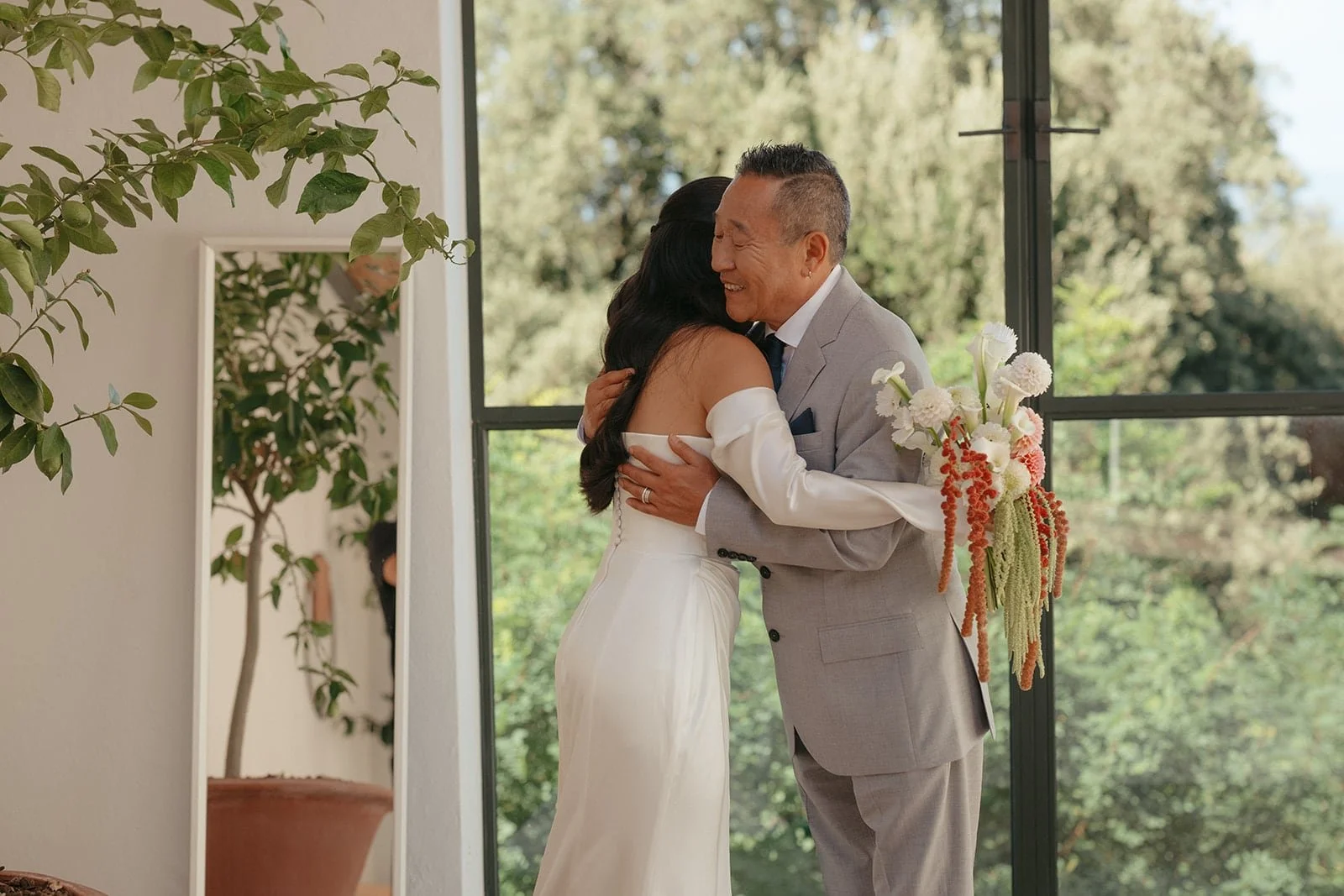 An intimate embrace between the bride and her father, captured in natural light during the wedding preparations.
