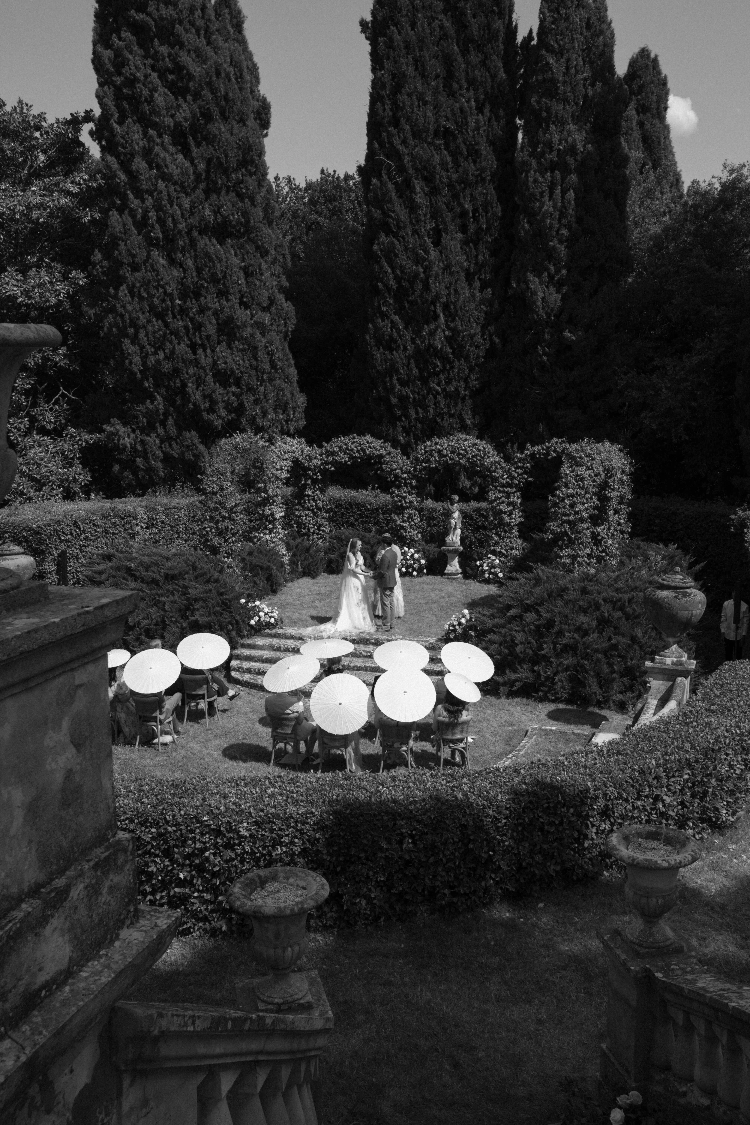 Intimate garden wedding ceremony in Italy, surrounded by formal greenery and timeless landscape design at Torre di Pila.