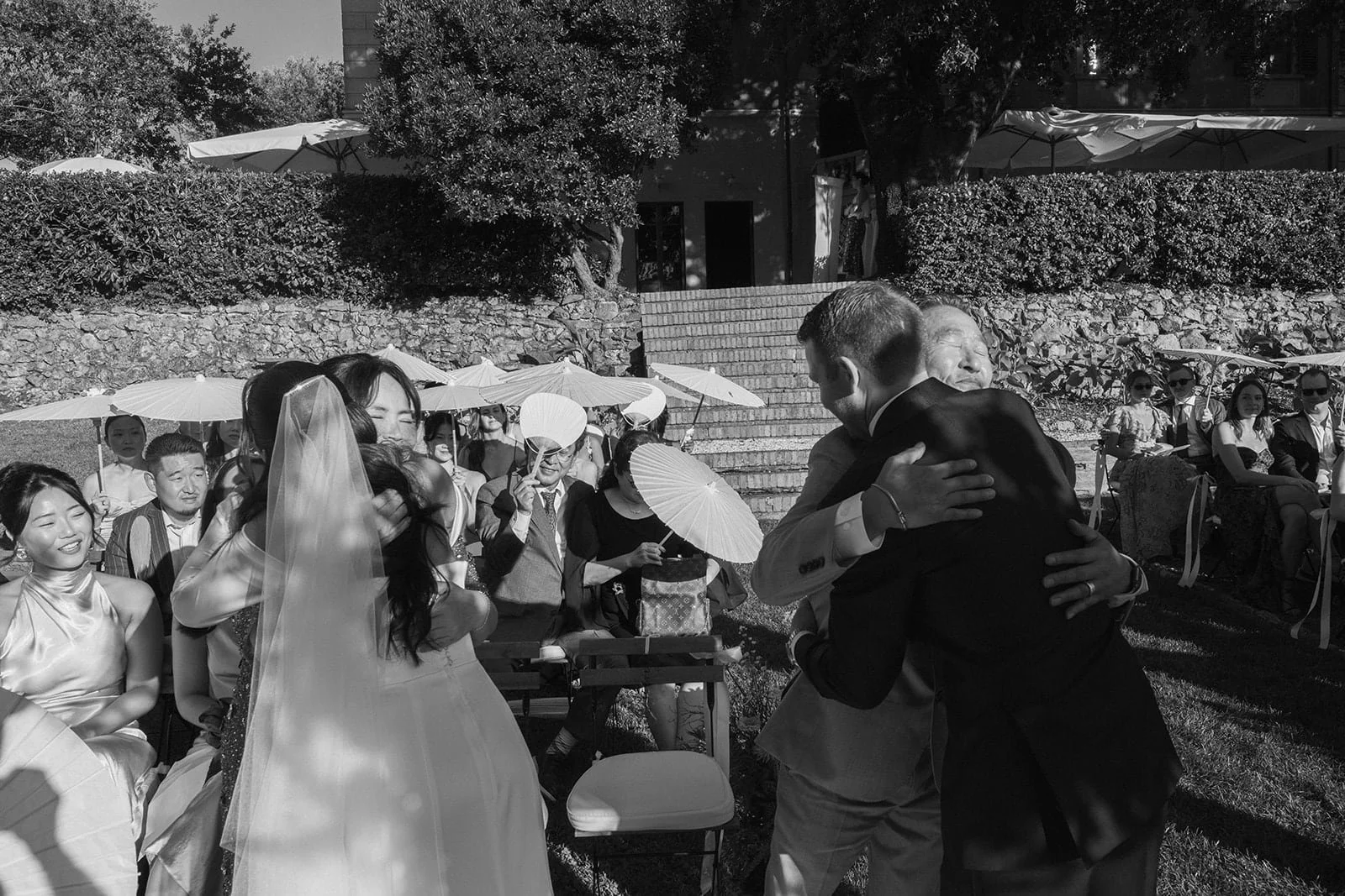 Emotional embraces between the couple and their loved ones immediately after the ceremony, photographed in black and white.