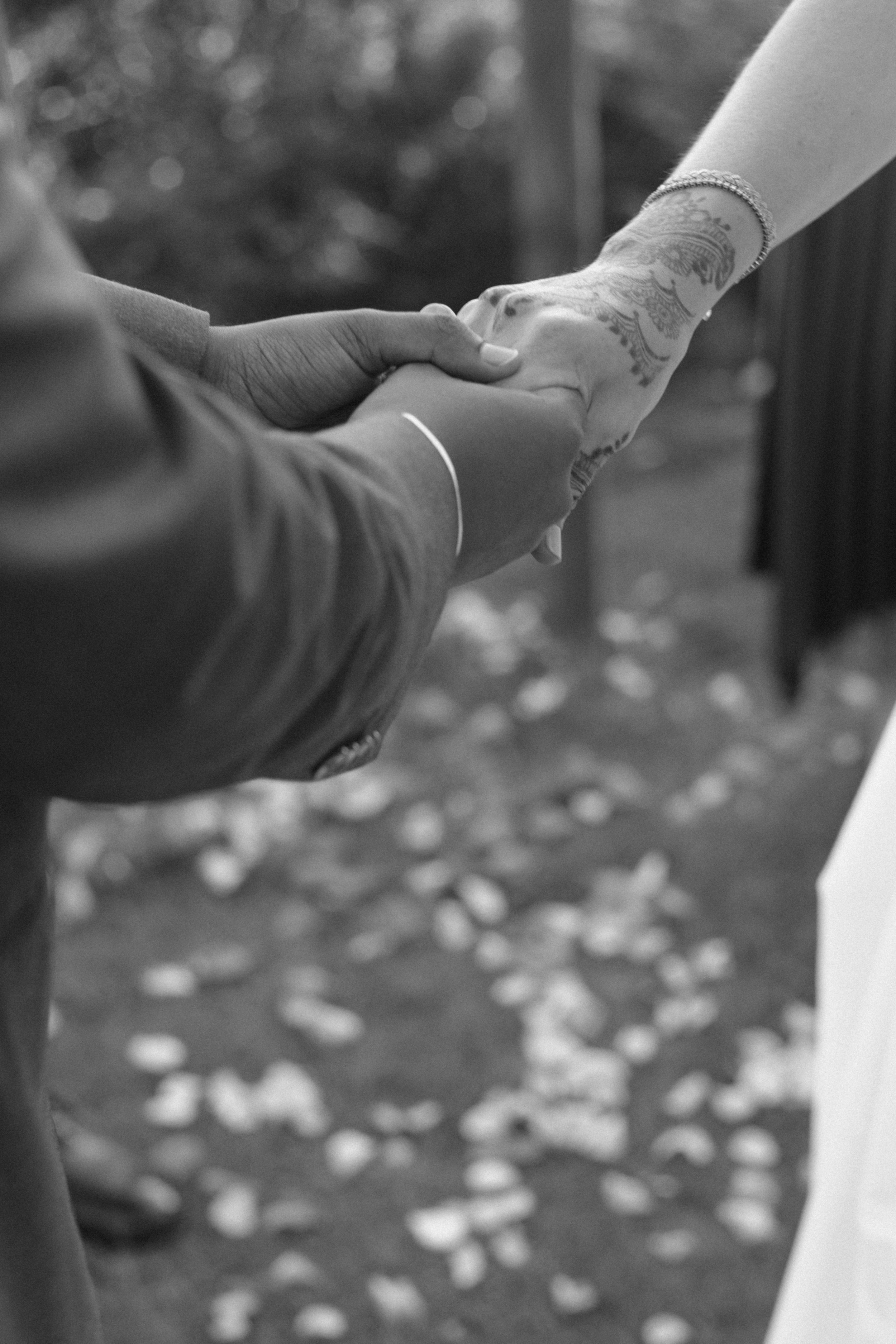 A refined close-up capturing intertwined hands and intricate mehndi during an intimate luxury Indian wedding in Tuscany, blending tradition with contemporary elegance.