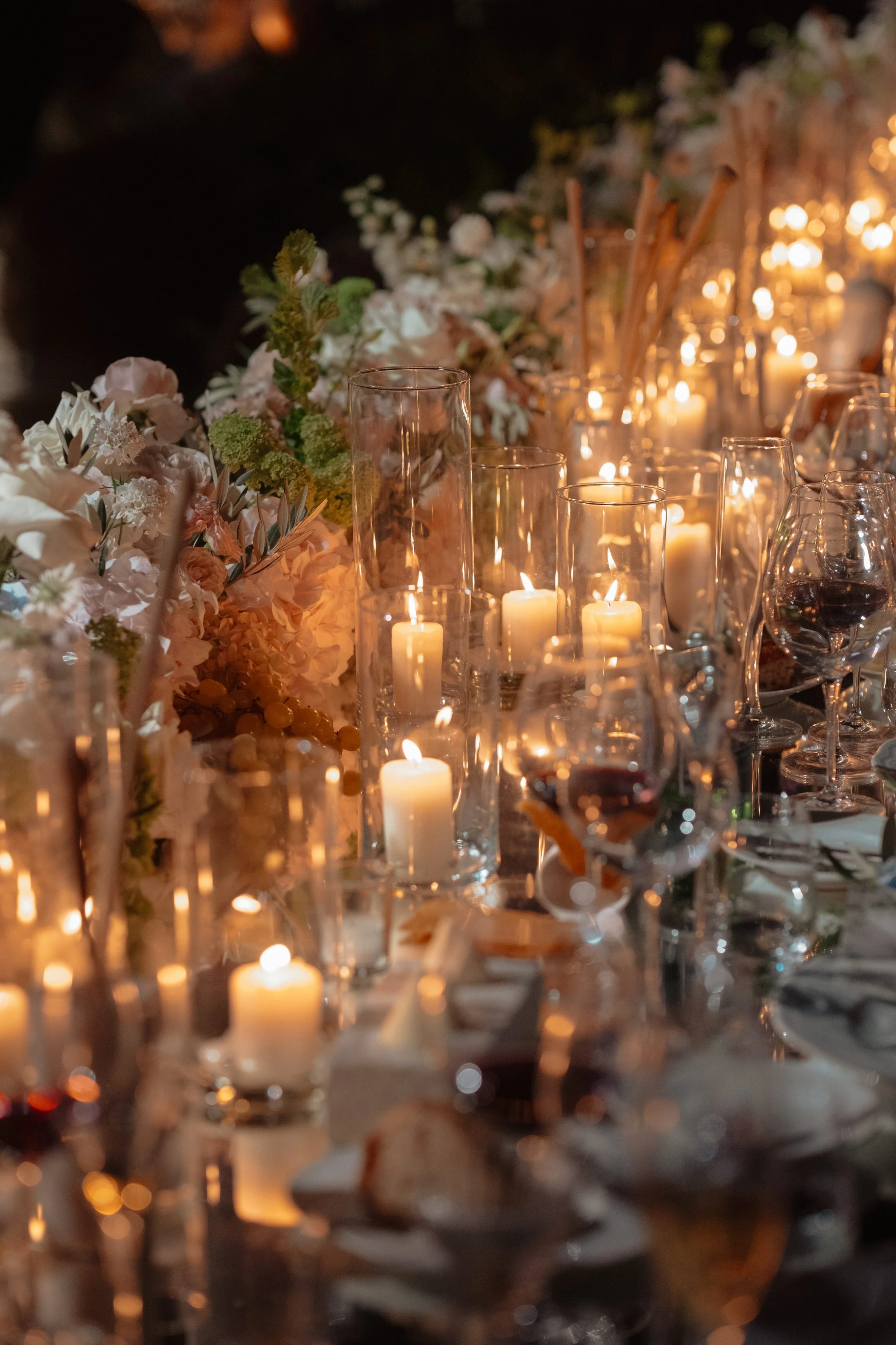Elegant candlelit wedding dinner with refined floral design, glassware, and warm lighting for a luxury destination wedding in Italy.
