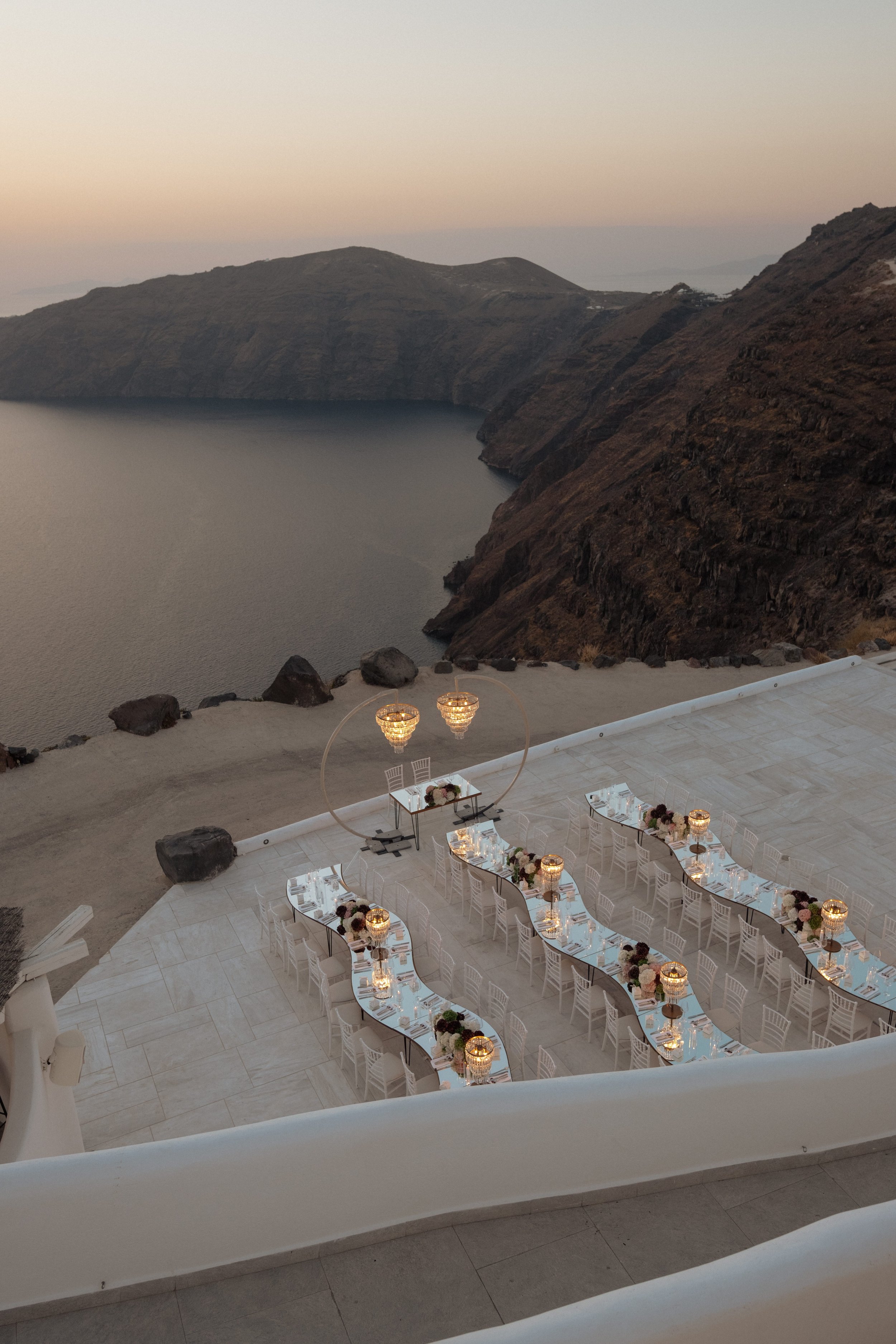 A breathtaking sunset wedding dinner at Rocabella Santorini, overlooking the caldera and captured in a refined, luxury destination wedding style.