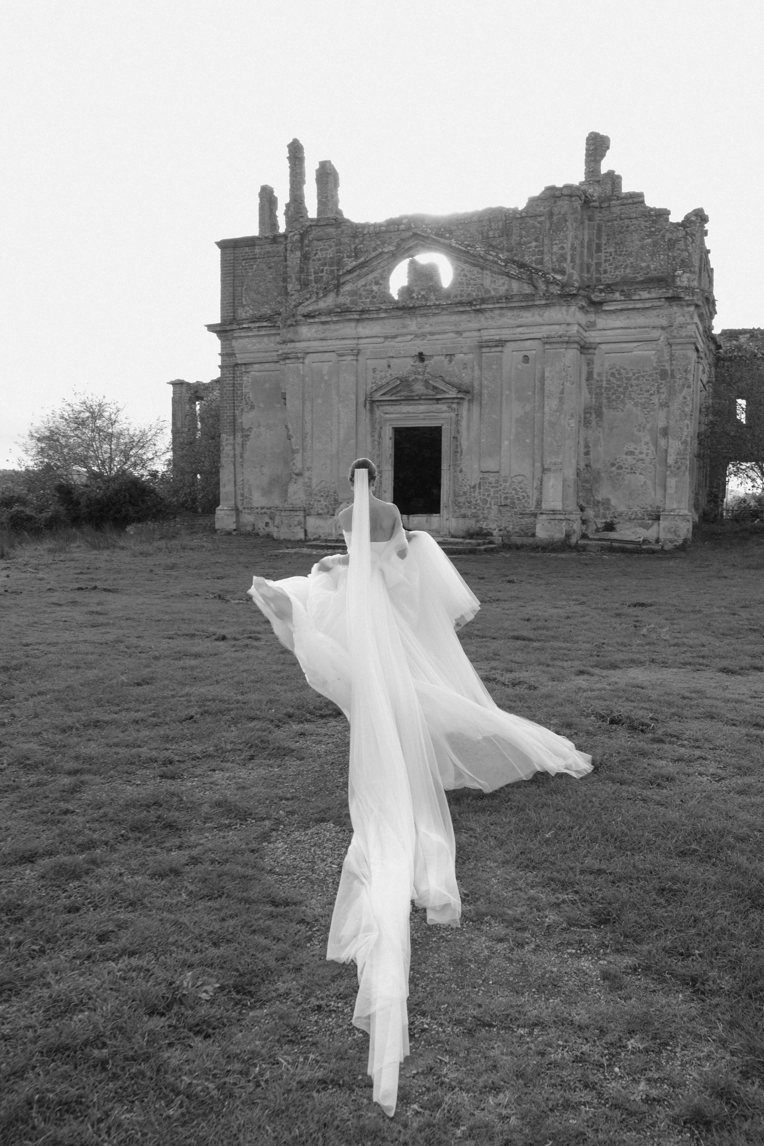 A dramatic bridal portrait in Tuscany, set against historic ruins, blending timeless architecture with modern bridal elegance.