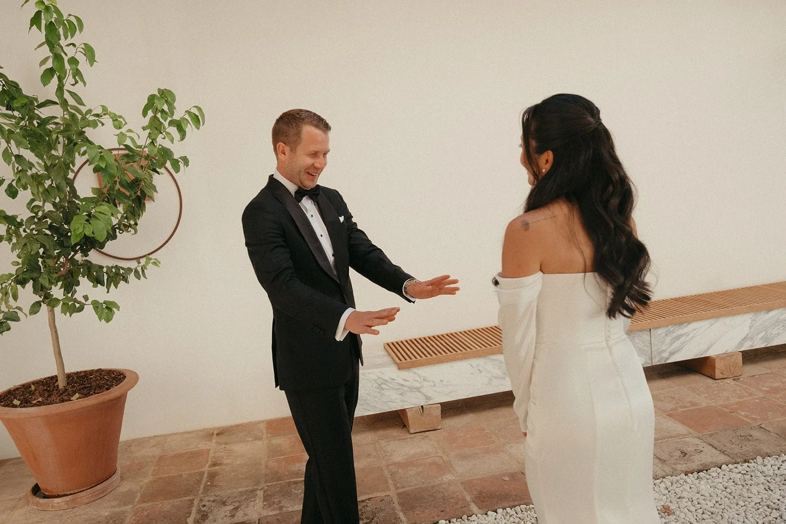 The groom reacts with emotion as he sees the bride for the first time, photographed inside Villa Lena with warm tones and minimalist surroundings.