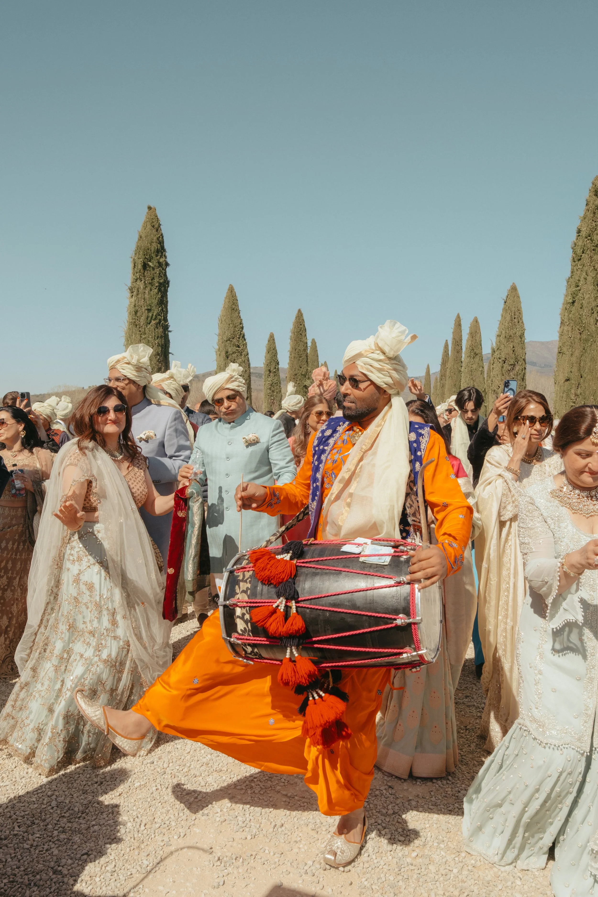 Joyful Indian wedding baraat in Tuscany with traditional dhol music, celebrating heritage rituals in a timeless Italian setting.