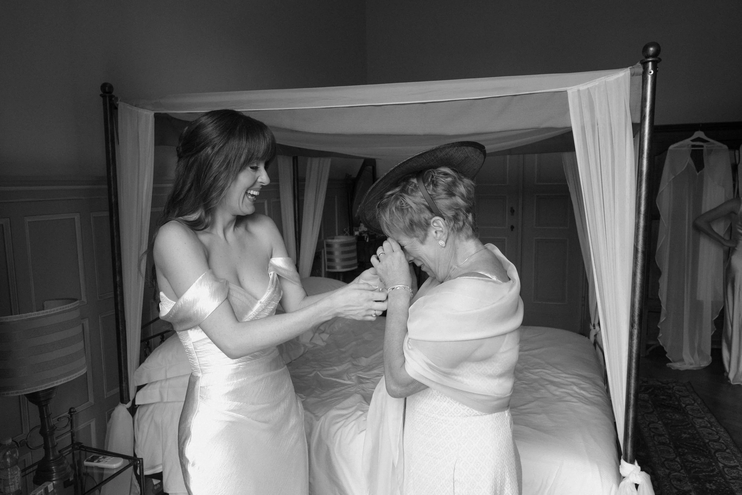 An intimate getting-ready moment at Villa Merlo Nero in Florence Tuscany between a bride and her mother, captured in a quiet bedroom setting, filled with emotion, laughter, and timeless documentary wedding photography.