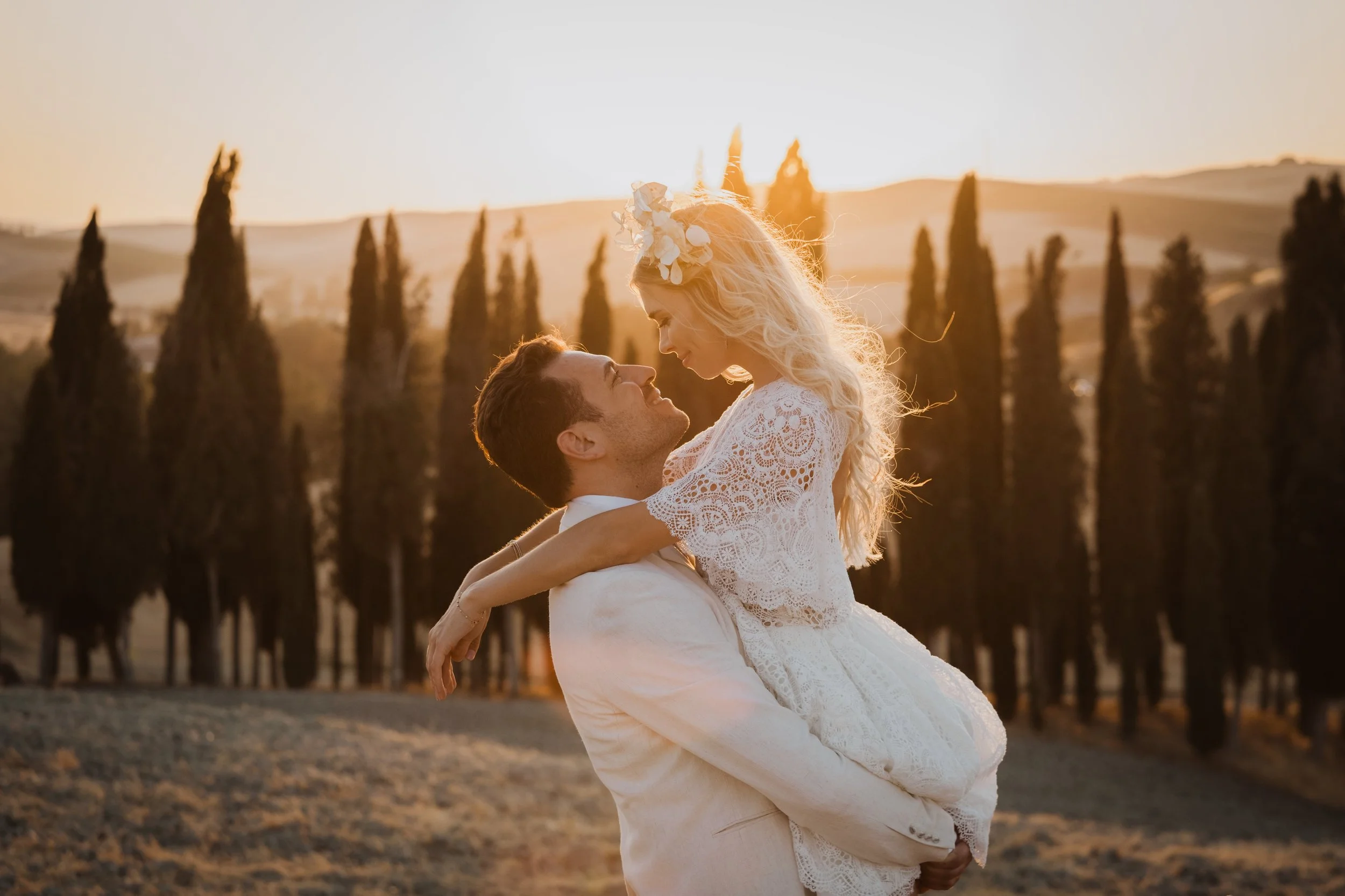 An intimate sunset elopement in Val d’Orcia, Tuscany, captured in warm golden light among cypress trees, celebrating love in a timeless Italian landscape.