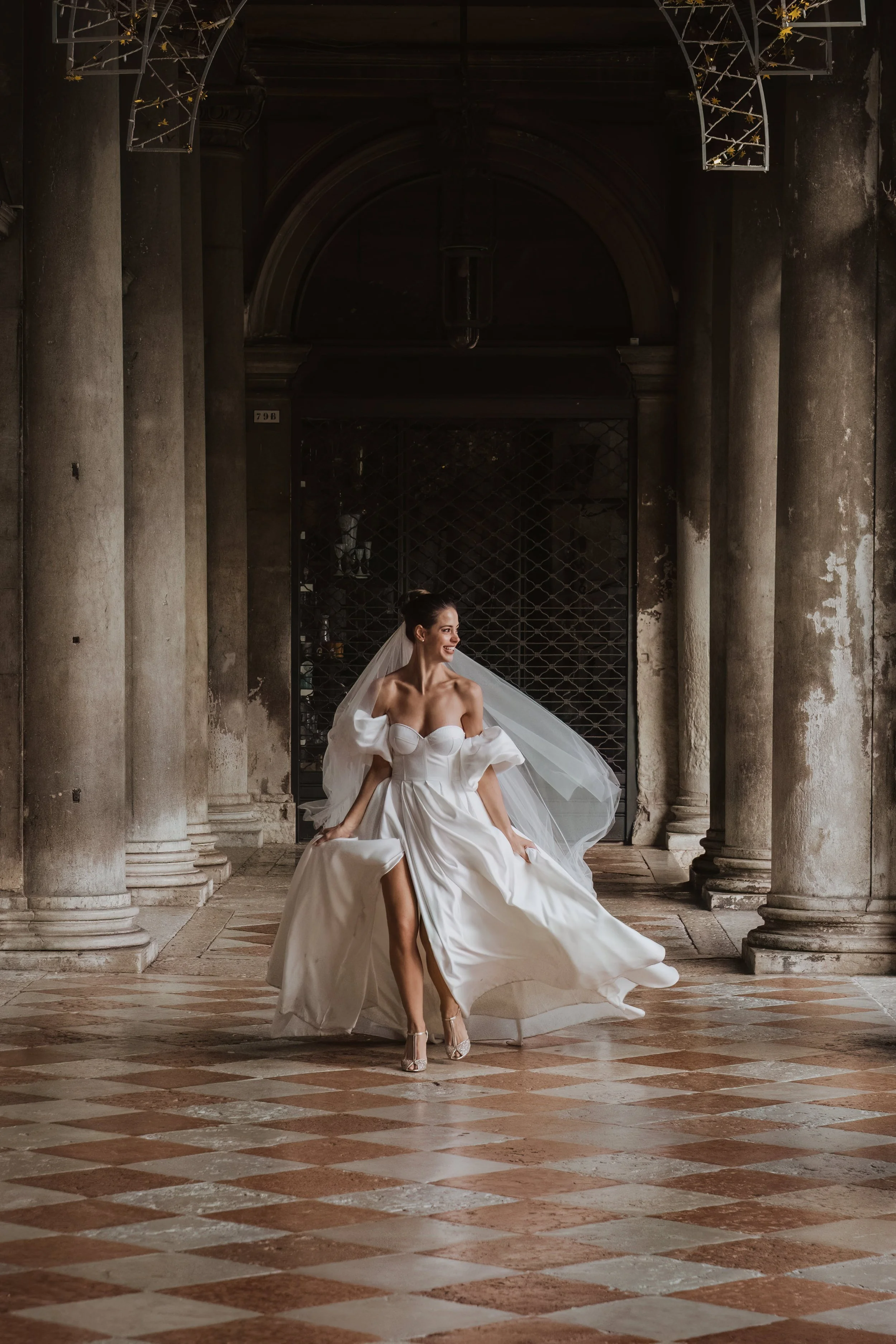 An editorial bridal portrait captured under the historic arcades of Venice, featuring a modern wedding dress and timeless Italian architecture during an intimate elopement.