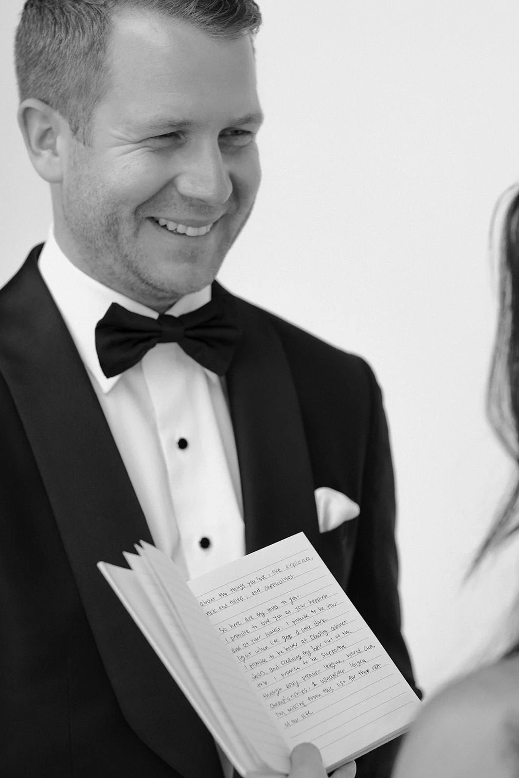 A close black and white portrait of the groom smiling as he listens to the vows, capturing a quiet and emotional moment during the ceremony in Tuscany.