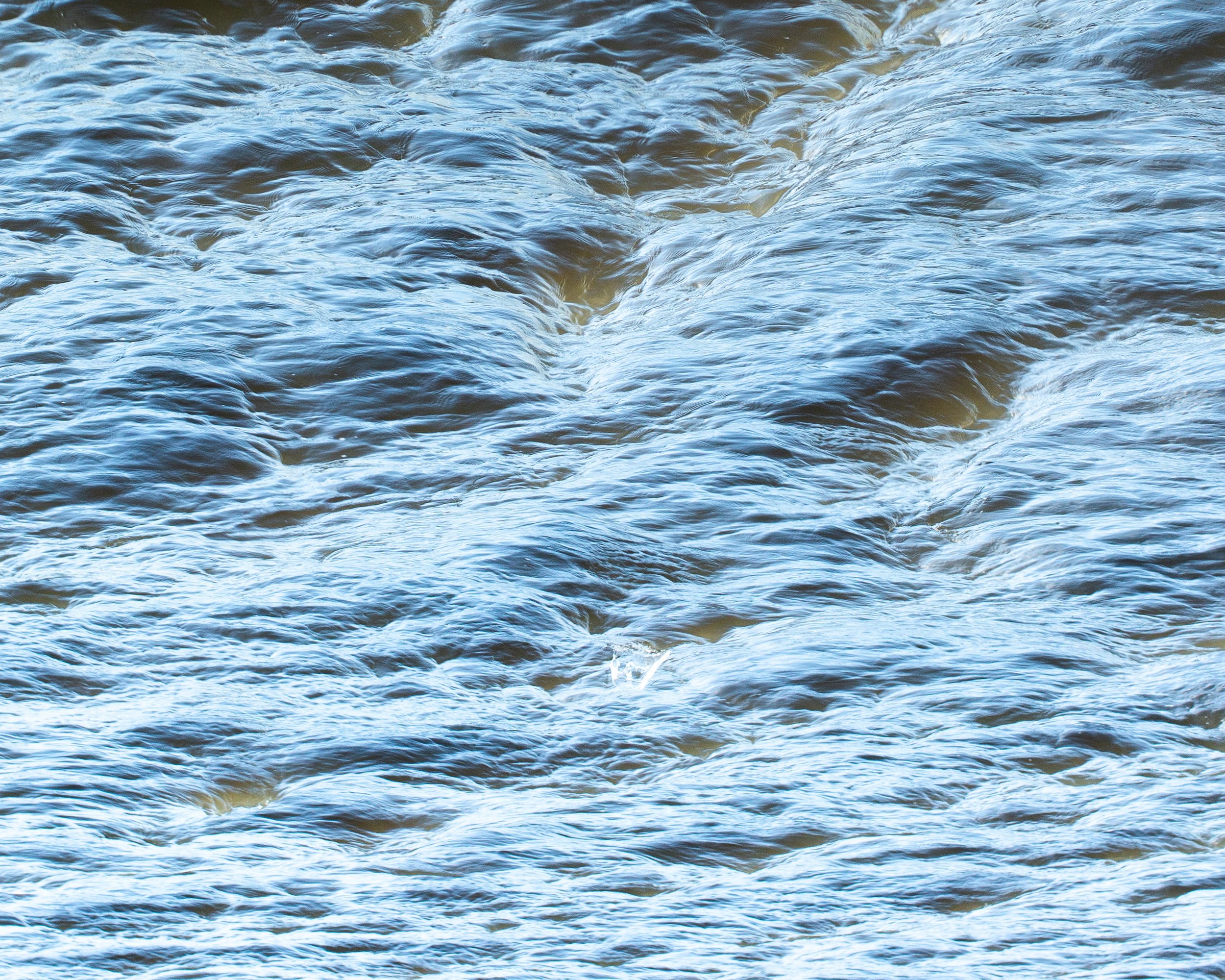 Blick auf bewegtes Wasser mit kleinen Wellen und Schaum