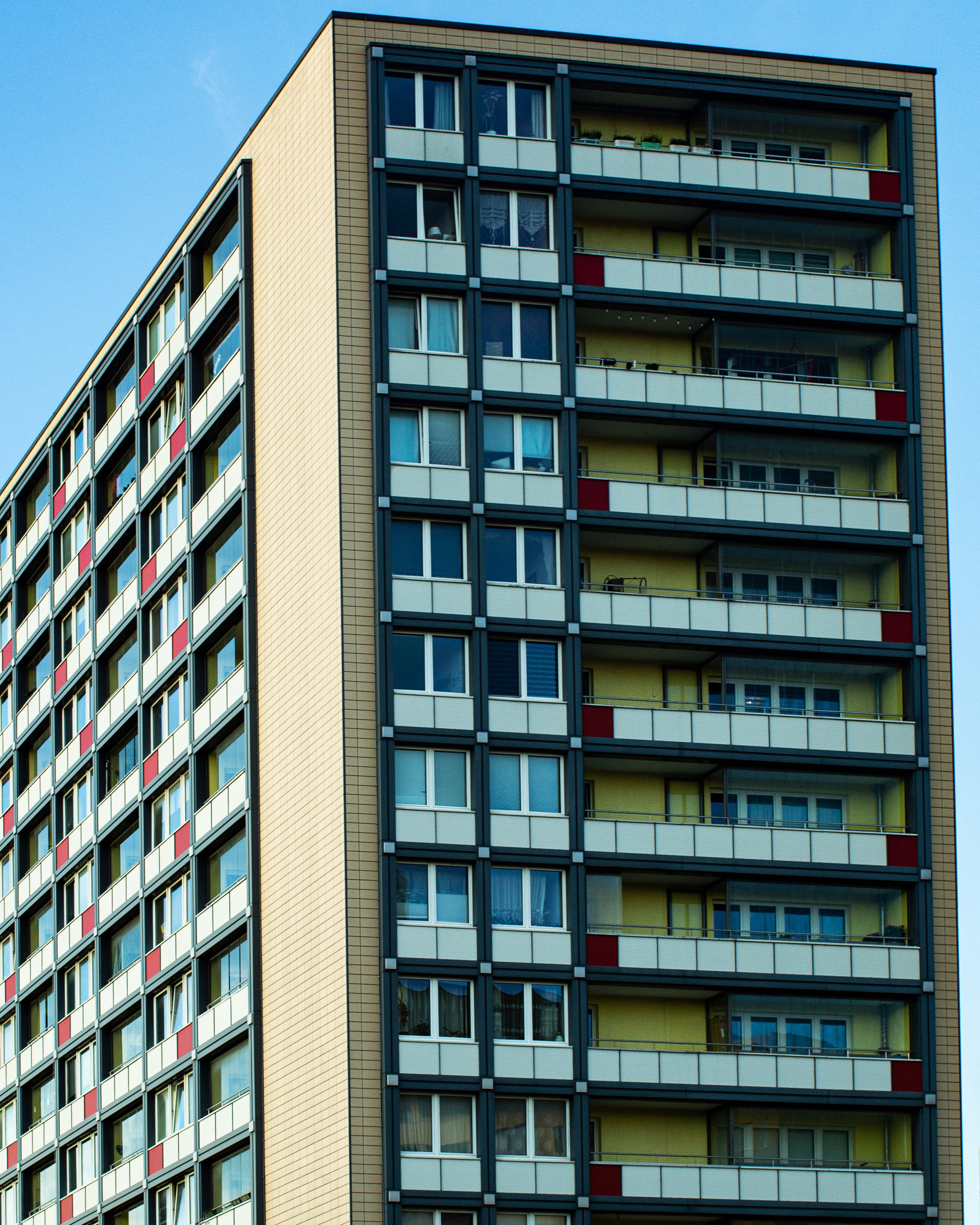 Hochhaus mit mehreren Balkonen und Fenstern gegen blauen Himmel