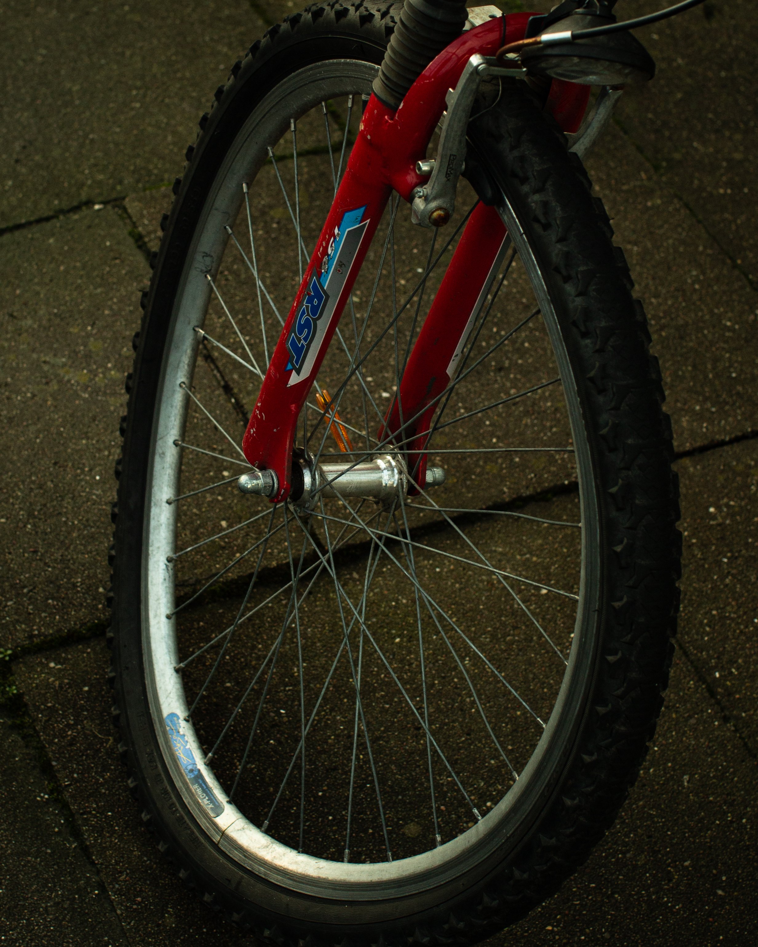 Vorderreifen eines roten Mountainbikes auf Kopf stehend auf gepflastertem Boden.