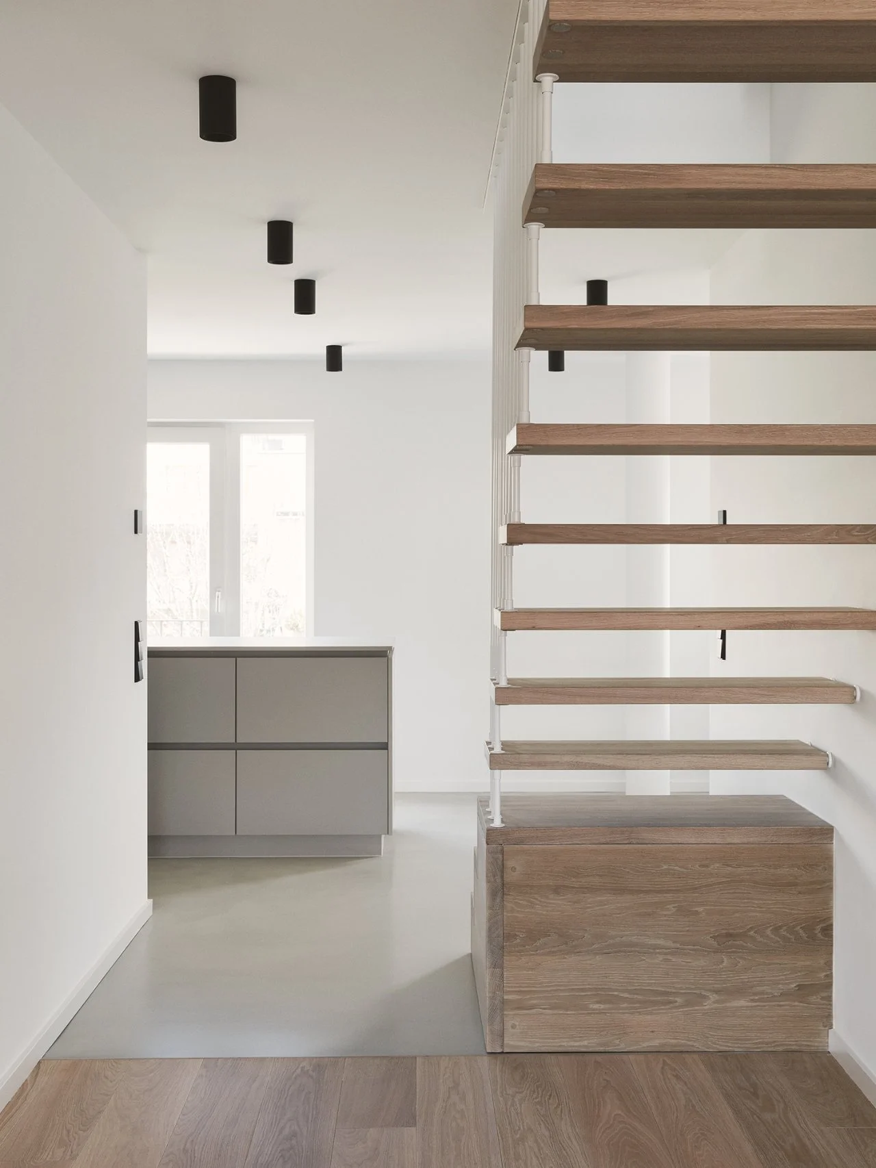 Moderne Innenarchitektur für private Wohnungen und Häuser mit heller, minimalistischer Raumgestaltung und offener Holztreppe