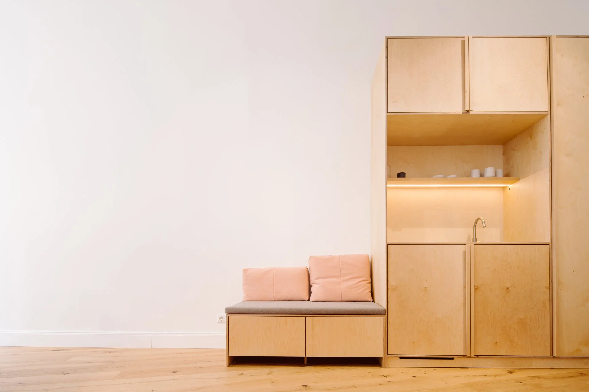 Minimalistische Holz-Wohnküche mit offenem Fach und Sitzbank.