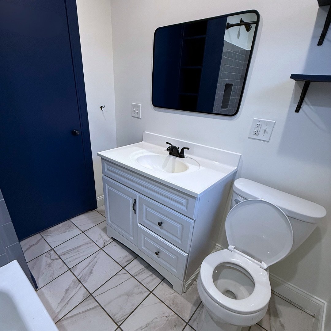 Clean, modern, and full of personality! 🖤💙 

This bathroom features dark blue and black accents, crisp white walls, and gray subway tile with a built-in niche for convenience. Plus, built-in shelving for extra storage.

A simple, functional space i