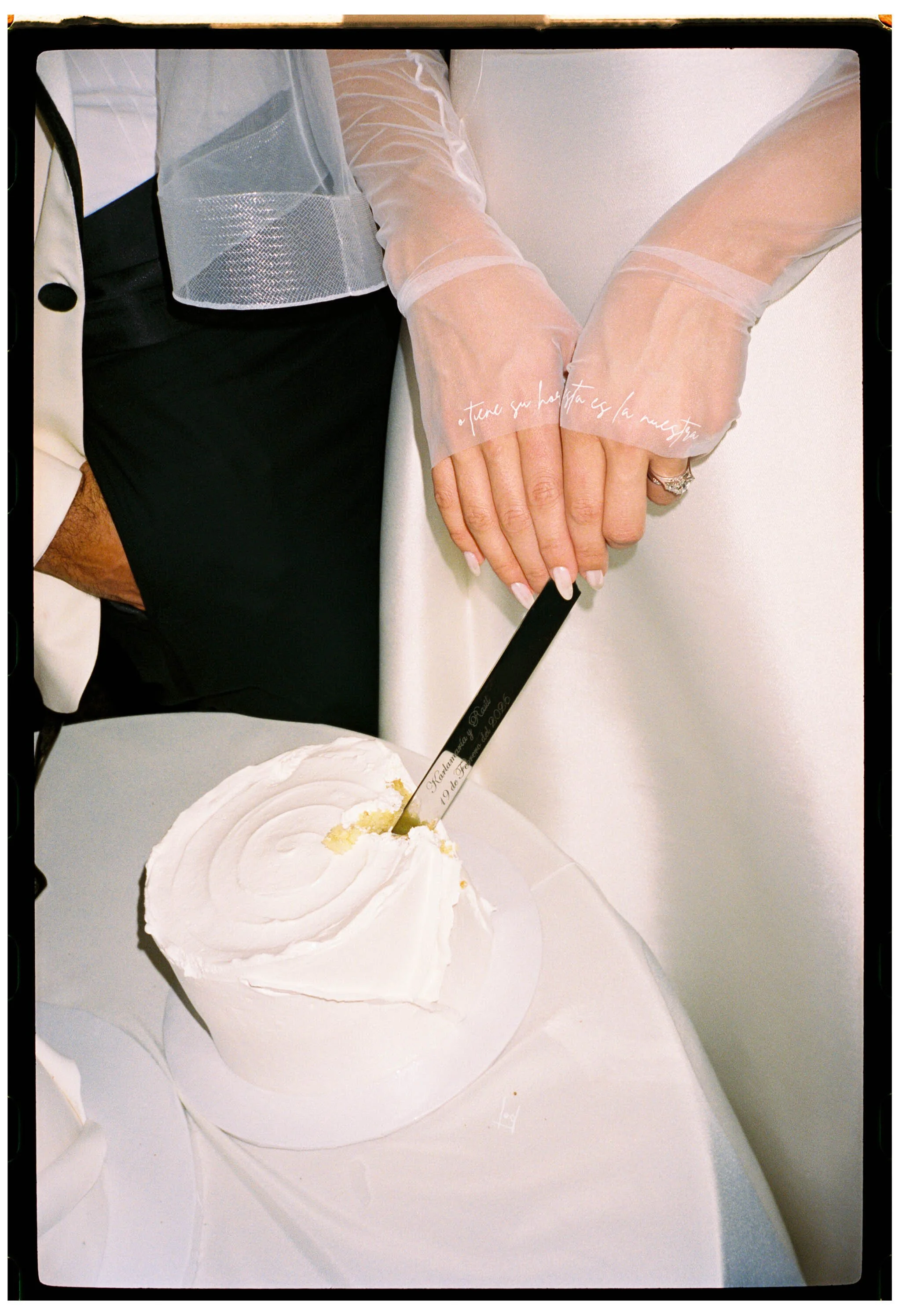 Close up of gloved hands cutting wedding cake captured on film