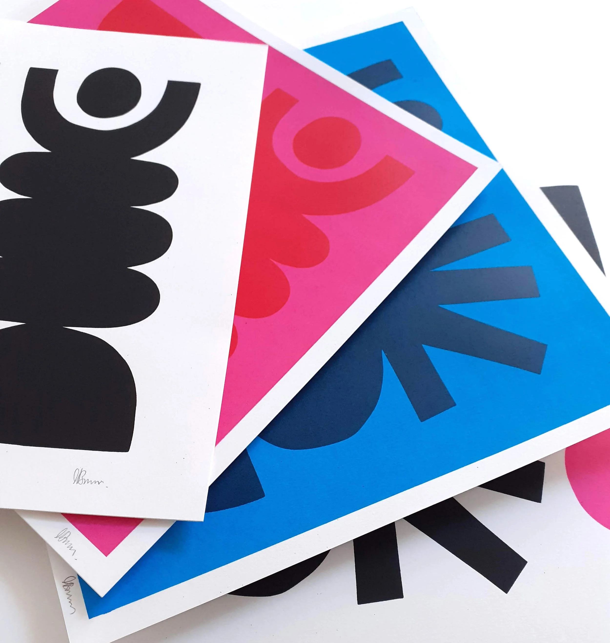 Colorful printed papers with bold black and pink text, arranged overlapping on a white and black background.