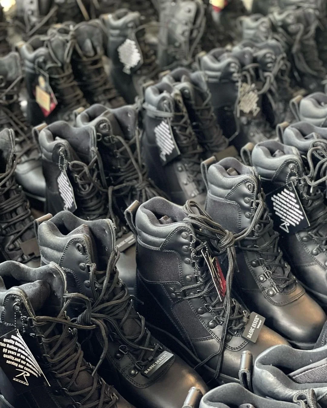 Rows of black tactical boots with tags and laces