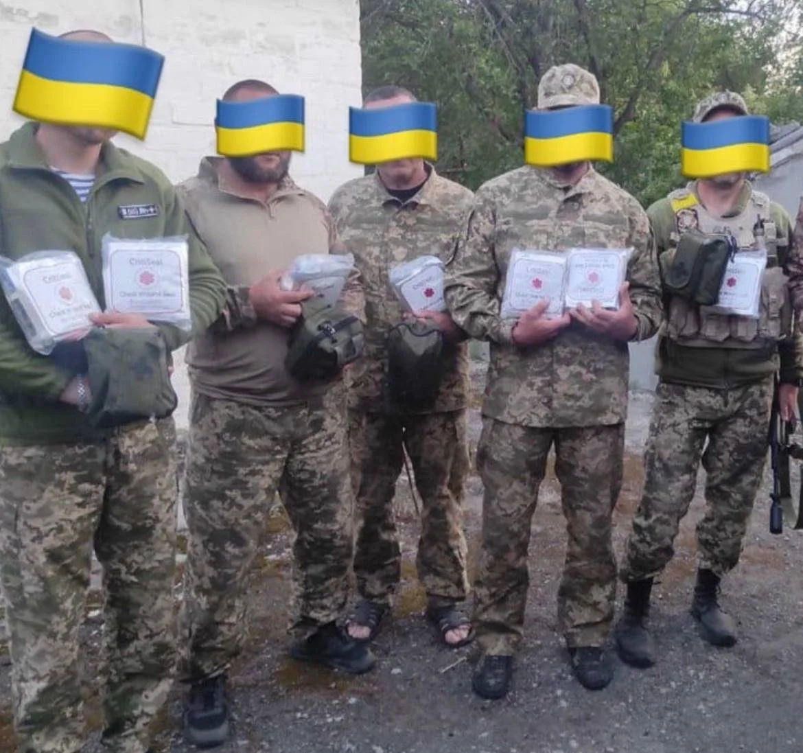 Group of soldiers in camouflage uniforms holding packaged military supplies